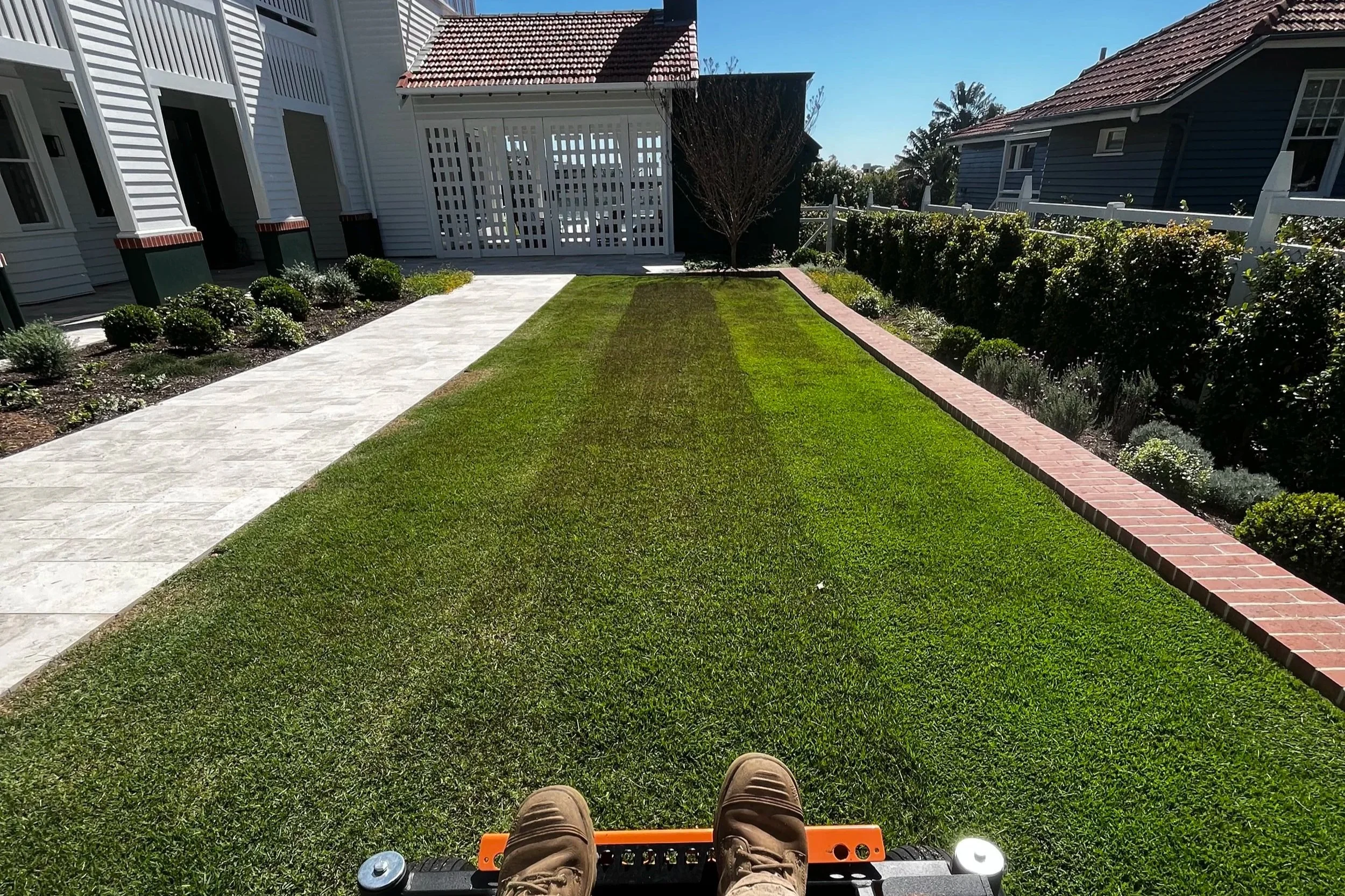 Ride on lawn mower, mowing a well-manicured grassy yard in a residential area or acreage