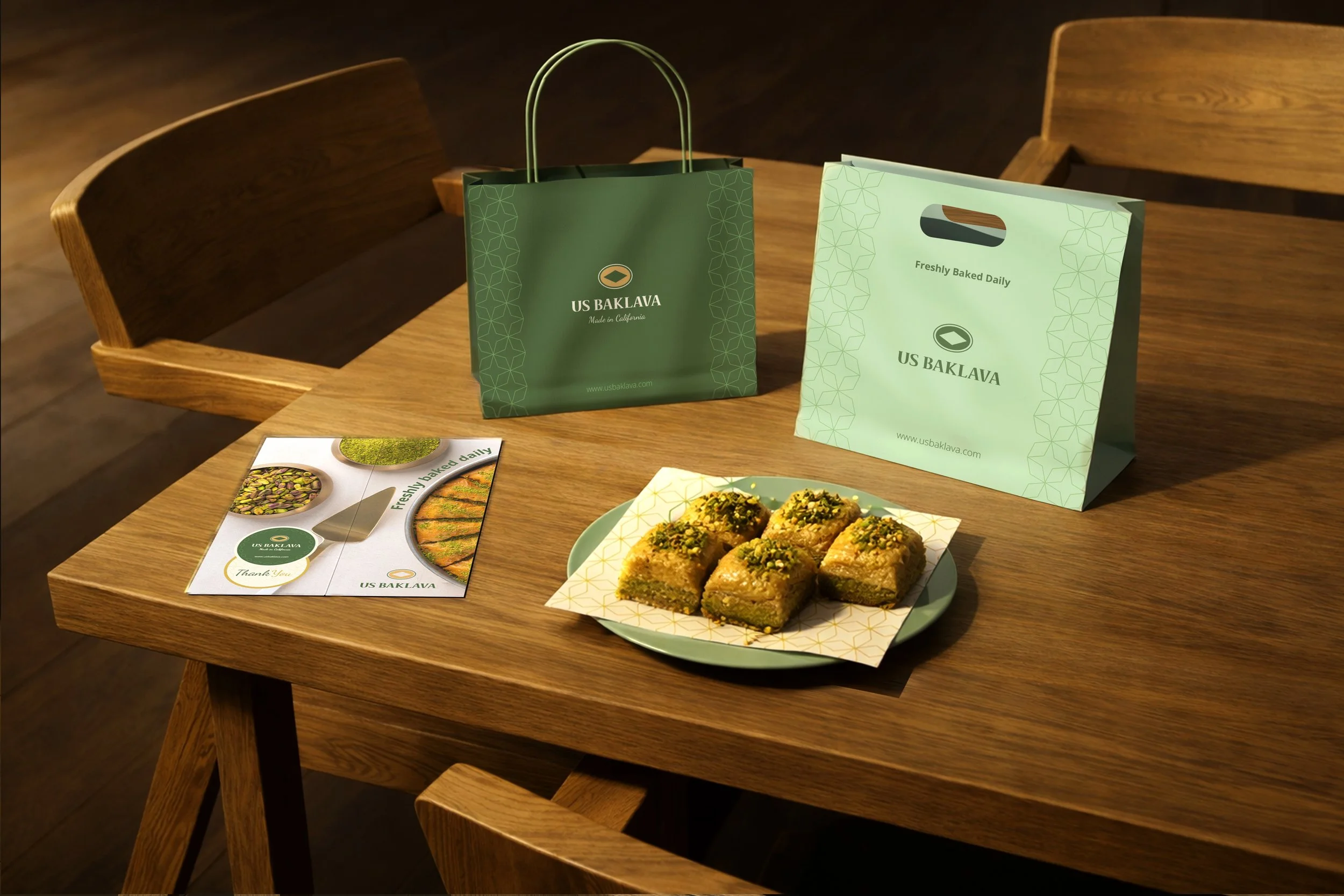 Table with pistachio baklava on a plate, promotional material, and shopping bags from US Baklava in a cozy setting.