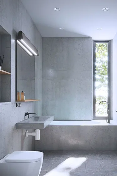 Modern bathroom with concrete walls, a rectangular sink, a toilet, a window with a view of trees, and minimal decor.