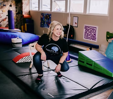 Woman with a back injury being assisted on a mattress in a therapy or rehabilitation center.