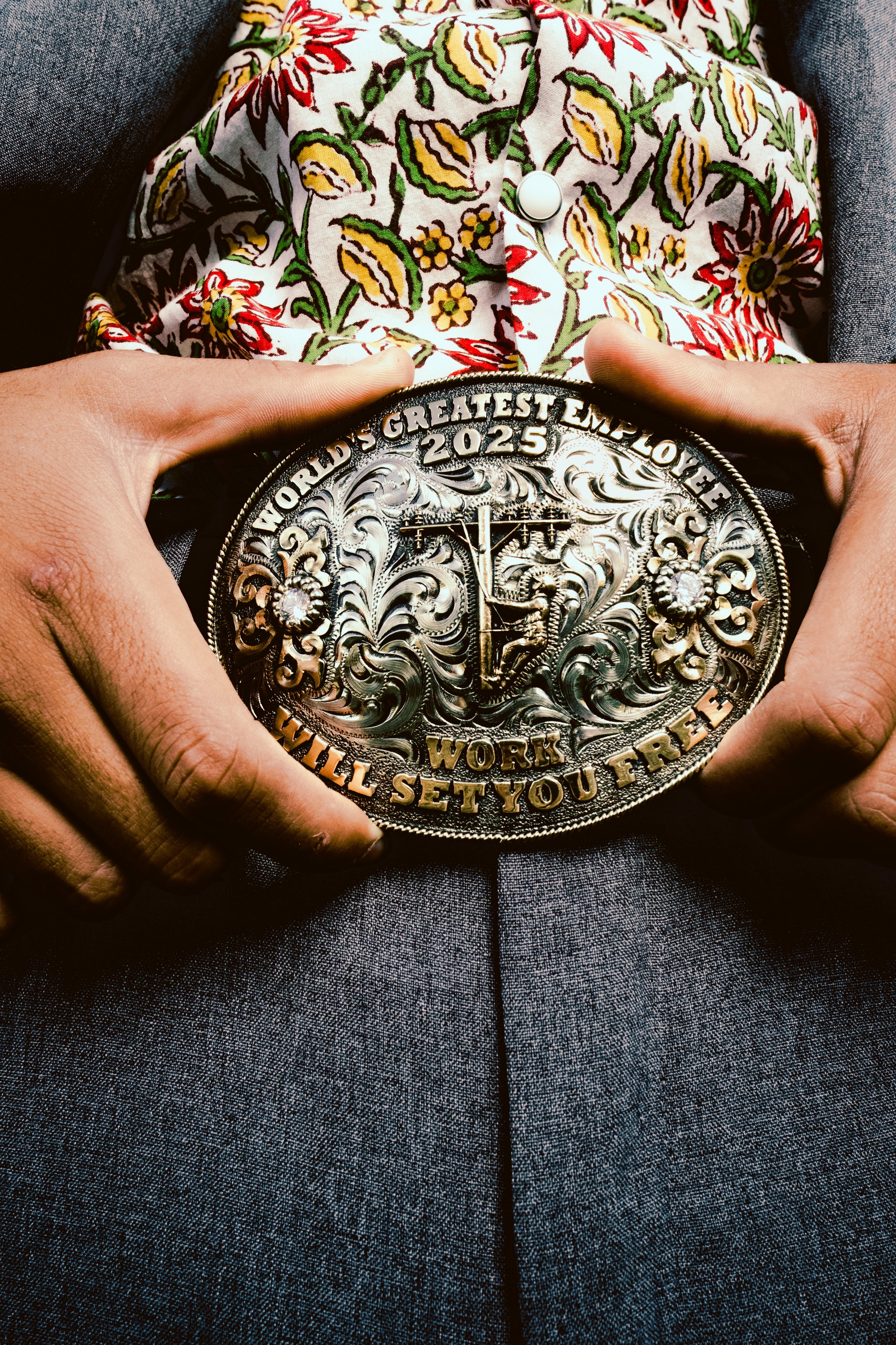 Person holding an ornate metal award with the inscription 'World's Greatest Employer 2025' and a clock design, wearing floral-patterned clothing.