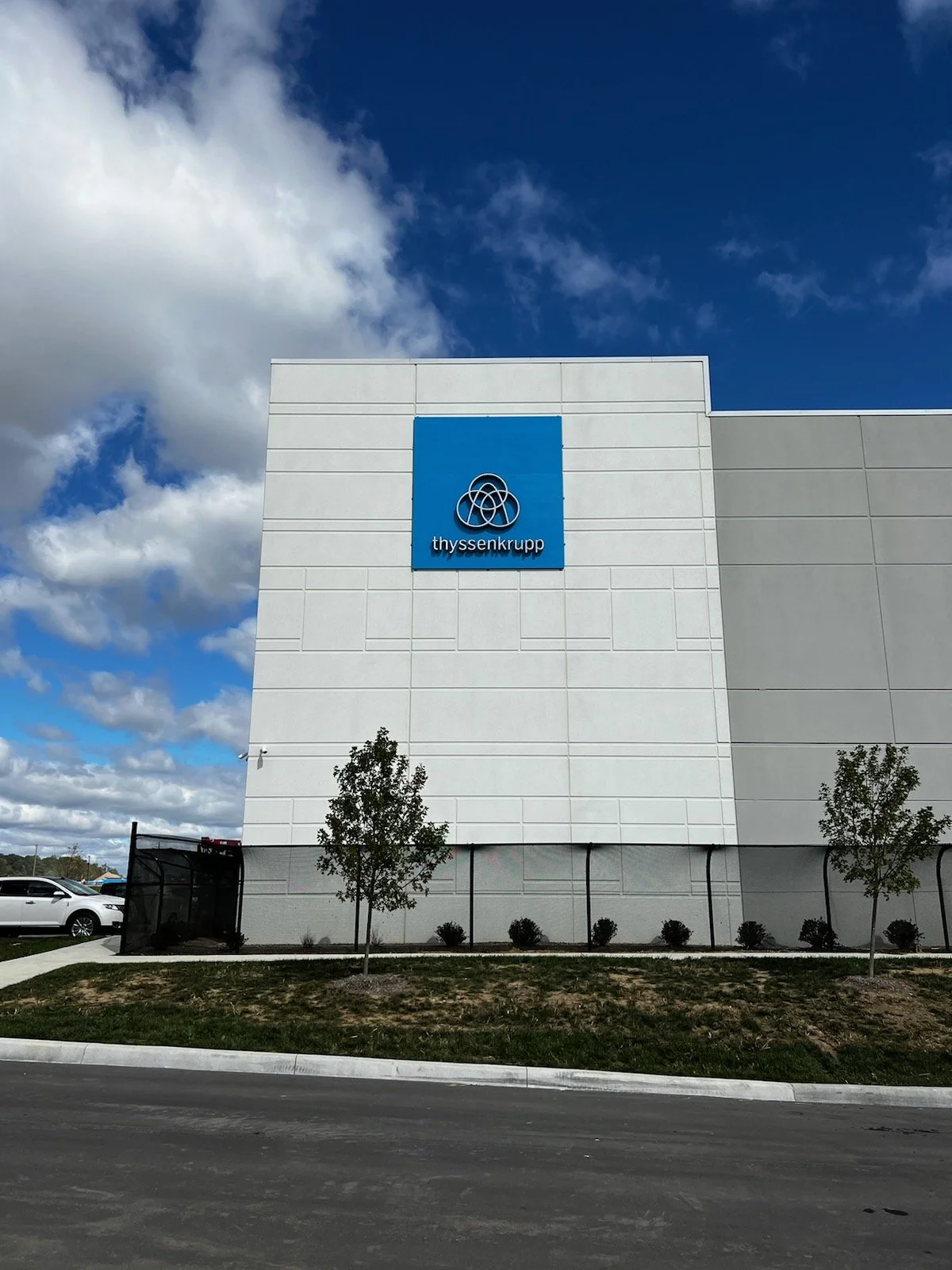 Exterior of a white building with a blue sign displaying the ThyssenKrupp logo and name