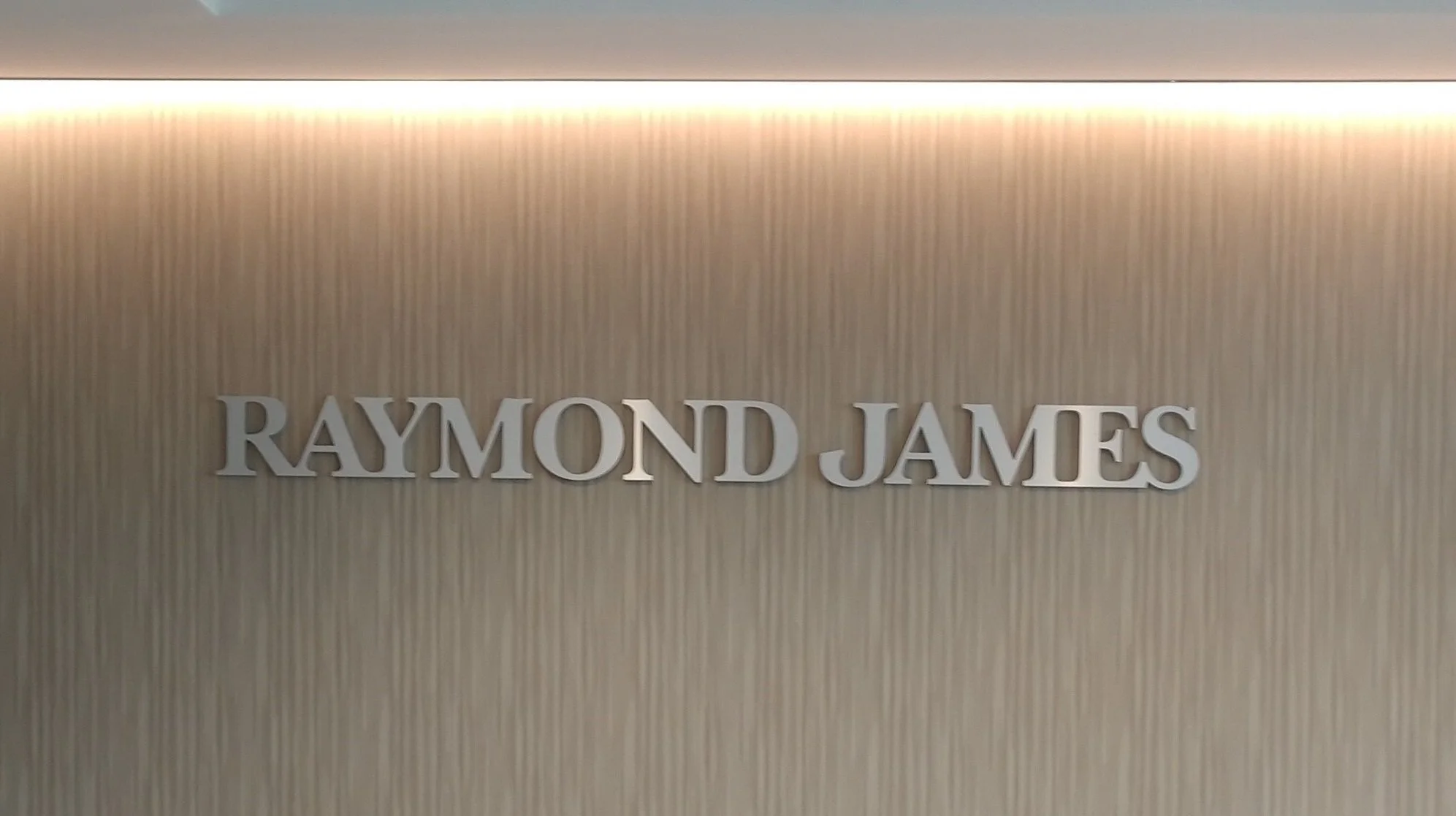 The wall displays the name "Raymond James" in metallic letters.