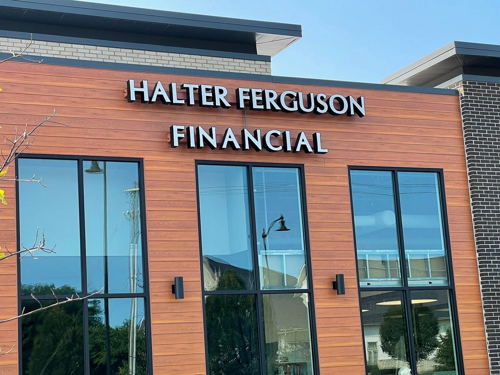 Exterior of a building with the sign 'Halter Ferguson Financial' on the wooden facade, featuring large glass windows and modern design.