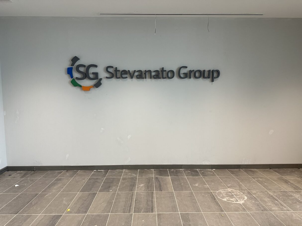 Sign on a plain wall displaying the logo and name of SG Stevanato Group.