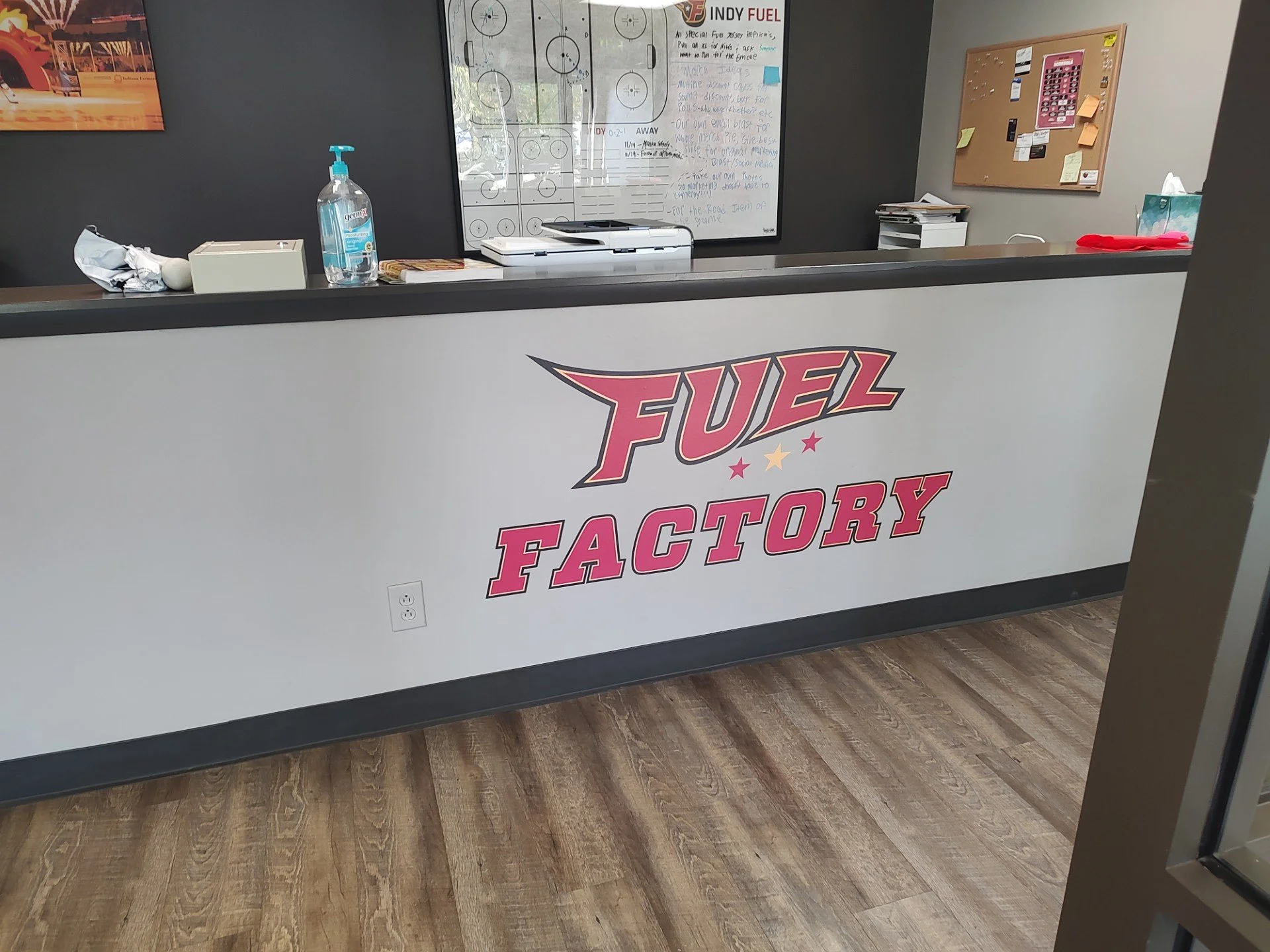 Reception counter with a sign that reads 'Fuel Factory' in bold pink and red lettering.