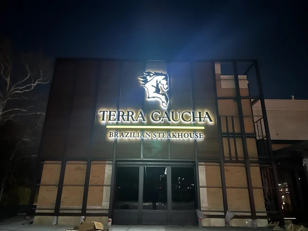 Night view of the illuminated sign for Terra Gaucha Brazilian Steakhouse on the building exterior, with a stylized horse logo above the text.