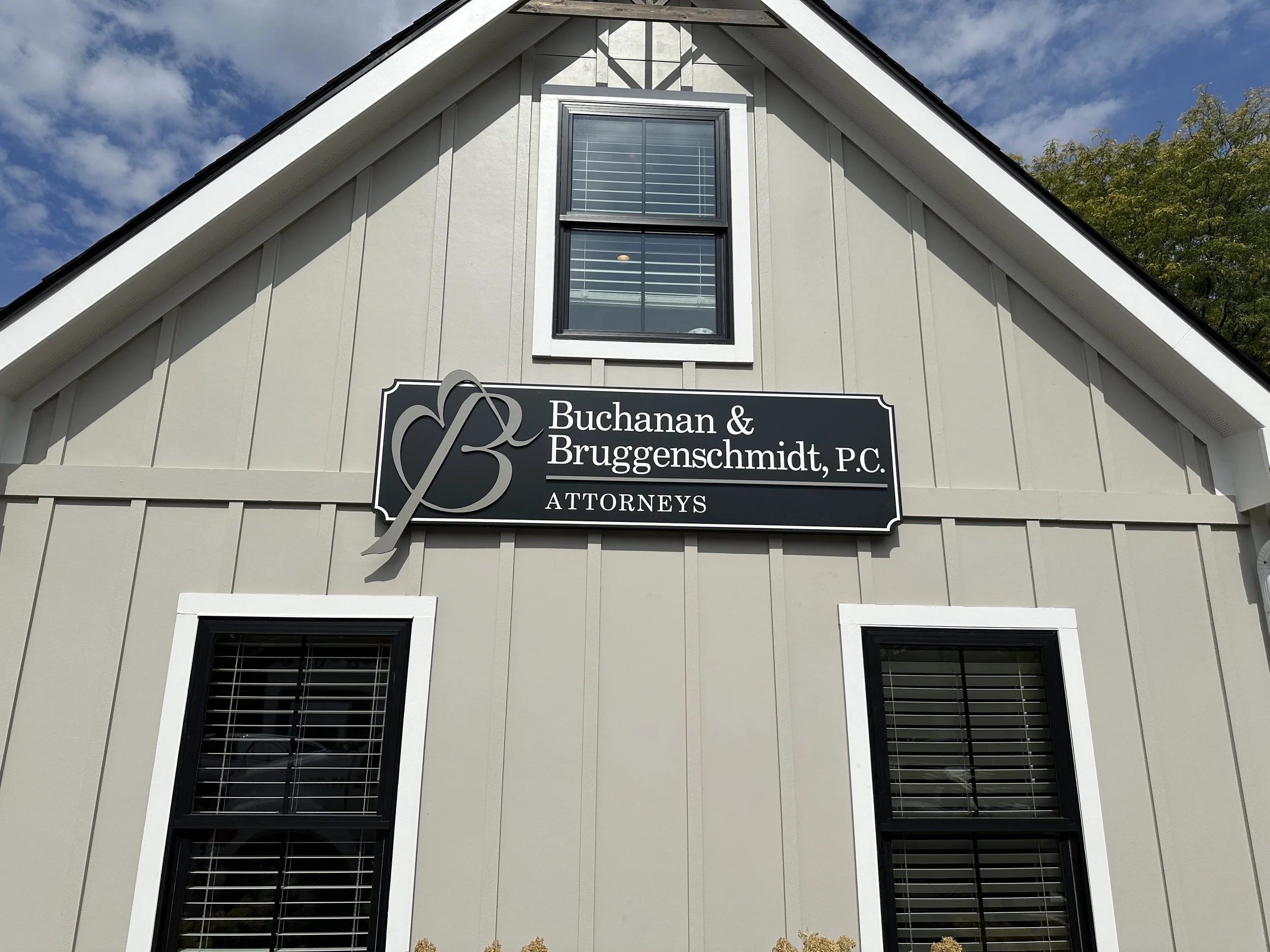 Sign on a beige building for Buchanan & Bruggenschmidt, P.C. Attorneys, with two windows below the sign and a gabled roof.