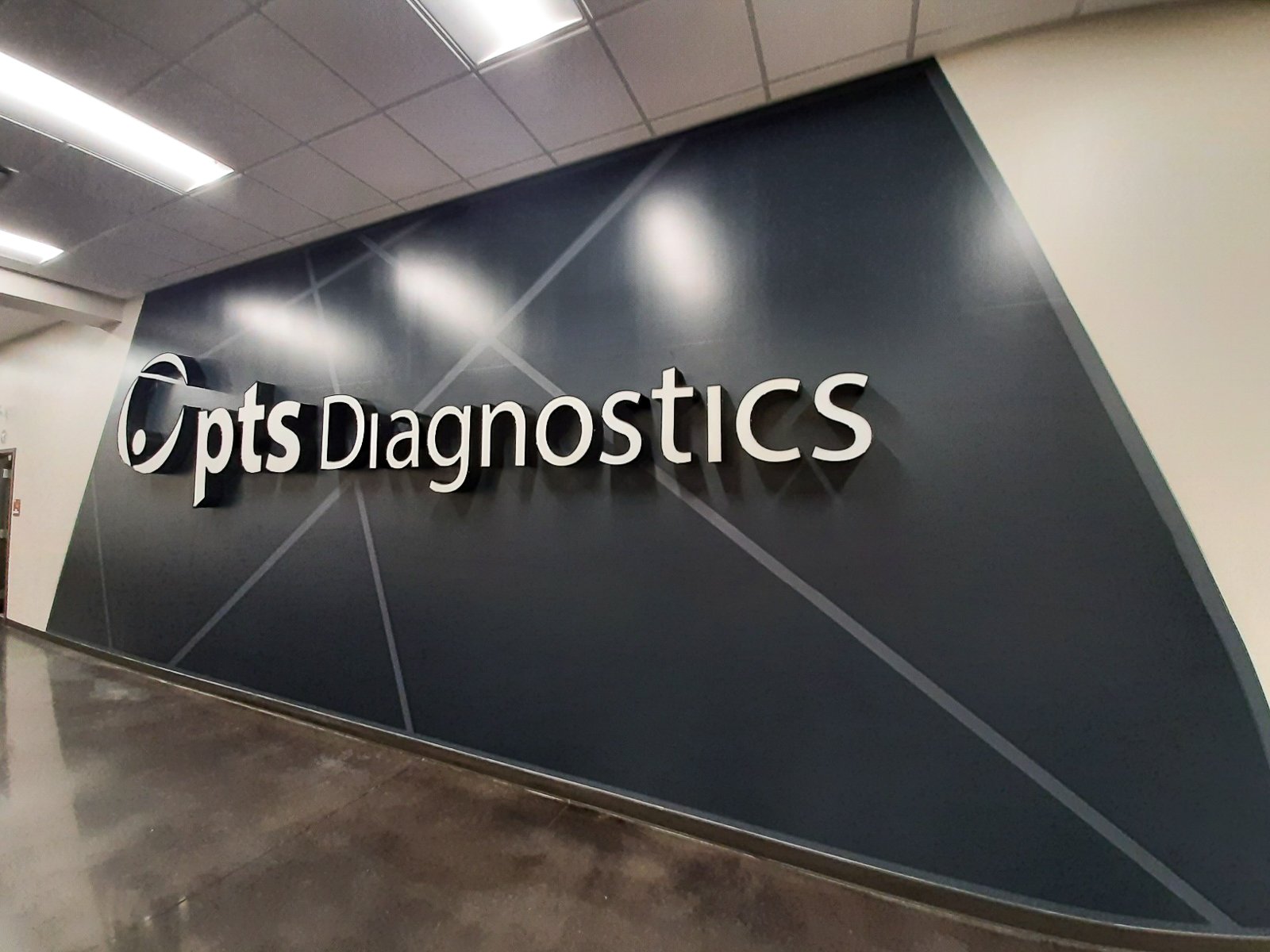 Interior wall of a diagnostics center with a large sign reading 'Optum Diagnostics' on a dark background with geometric design.