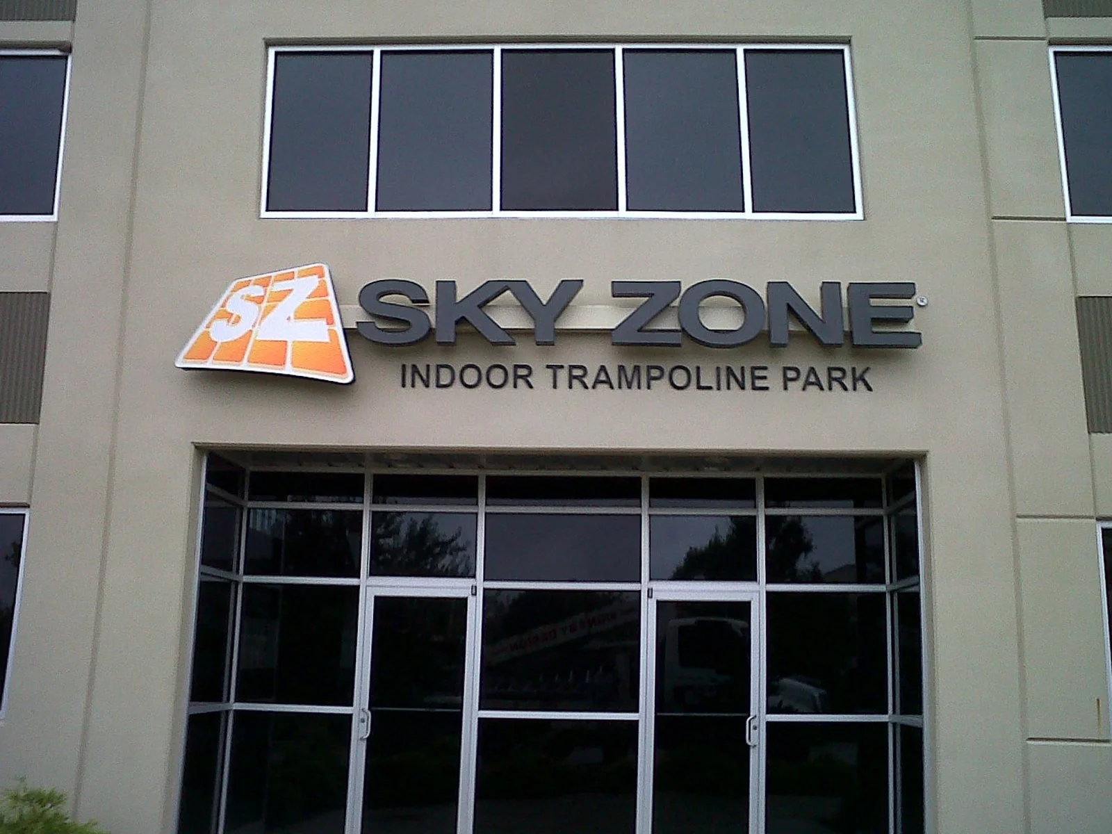 Sign for Sky Zone Indoor Trampoline Park on the front of a building with glass doors and windows.