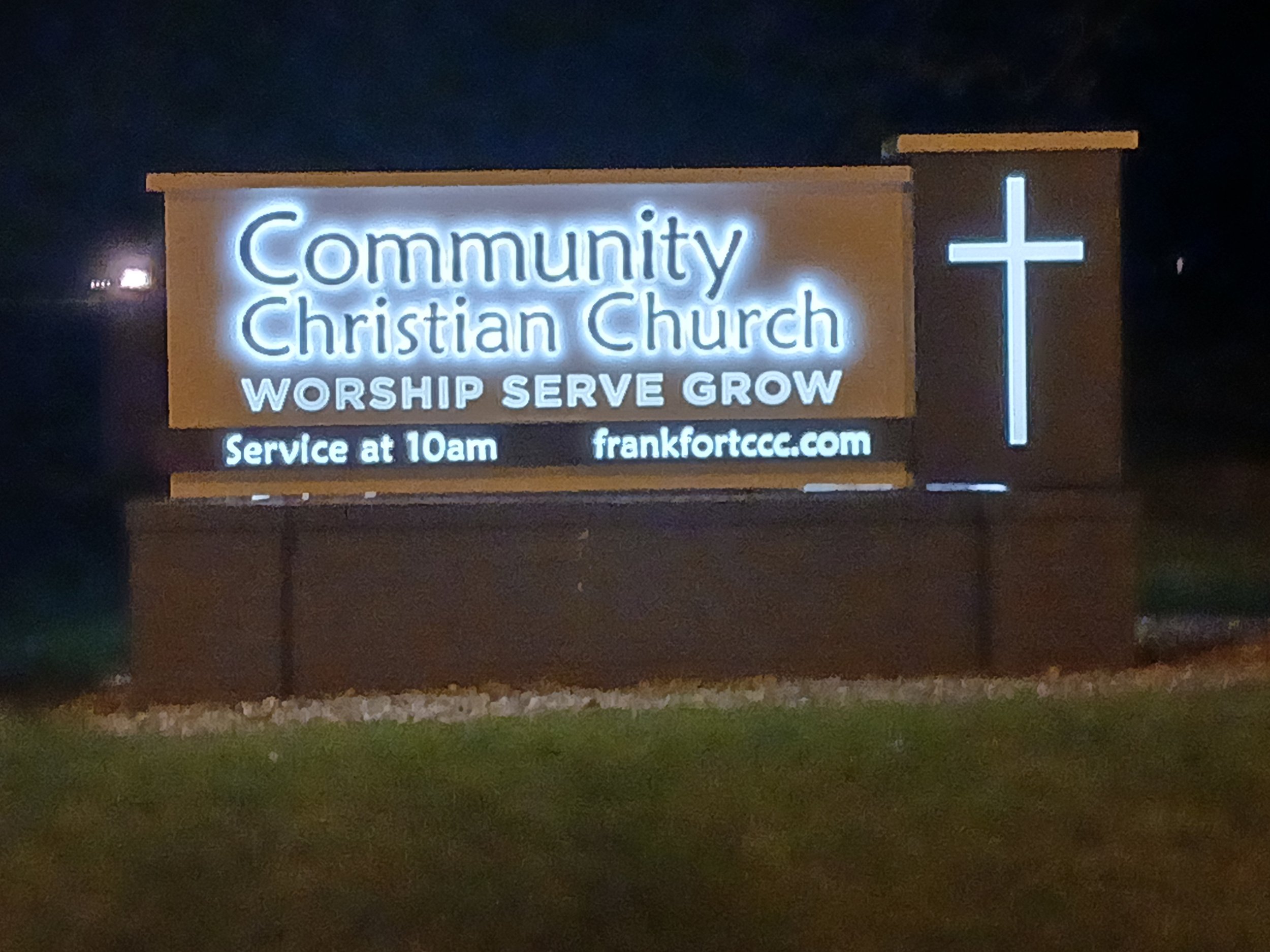 Illuminated sign for Community Christian Church at night, with the words 'WORSHIP SERVE GROW', a cross symbol, and service time at 10am, along with the website link frankfortcc.com.