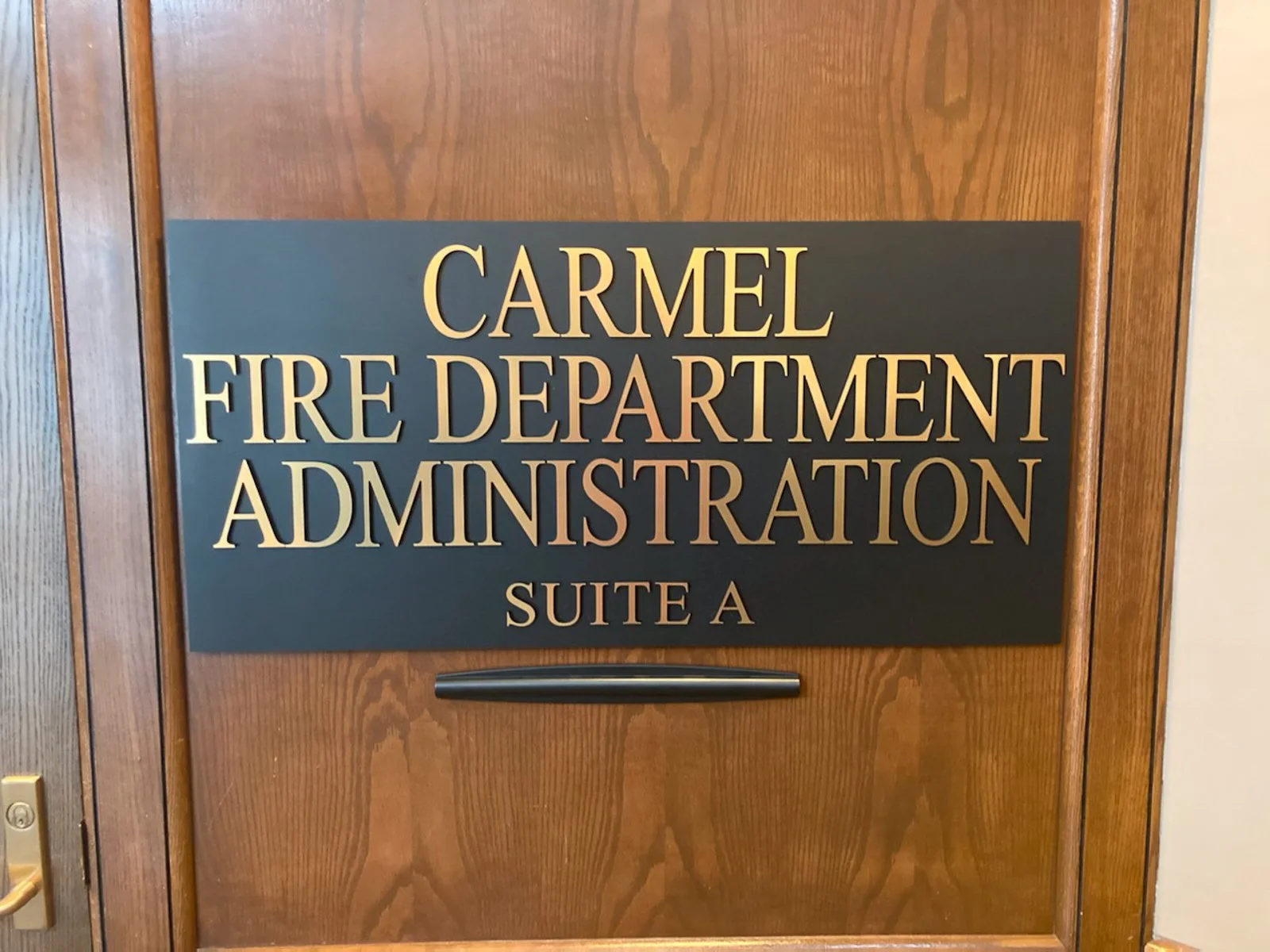 Sign on wooden door reads 'CARMEL FIRE DEPARTMENT ADMINISTRATION SUITE A'.