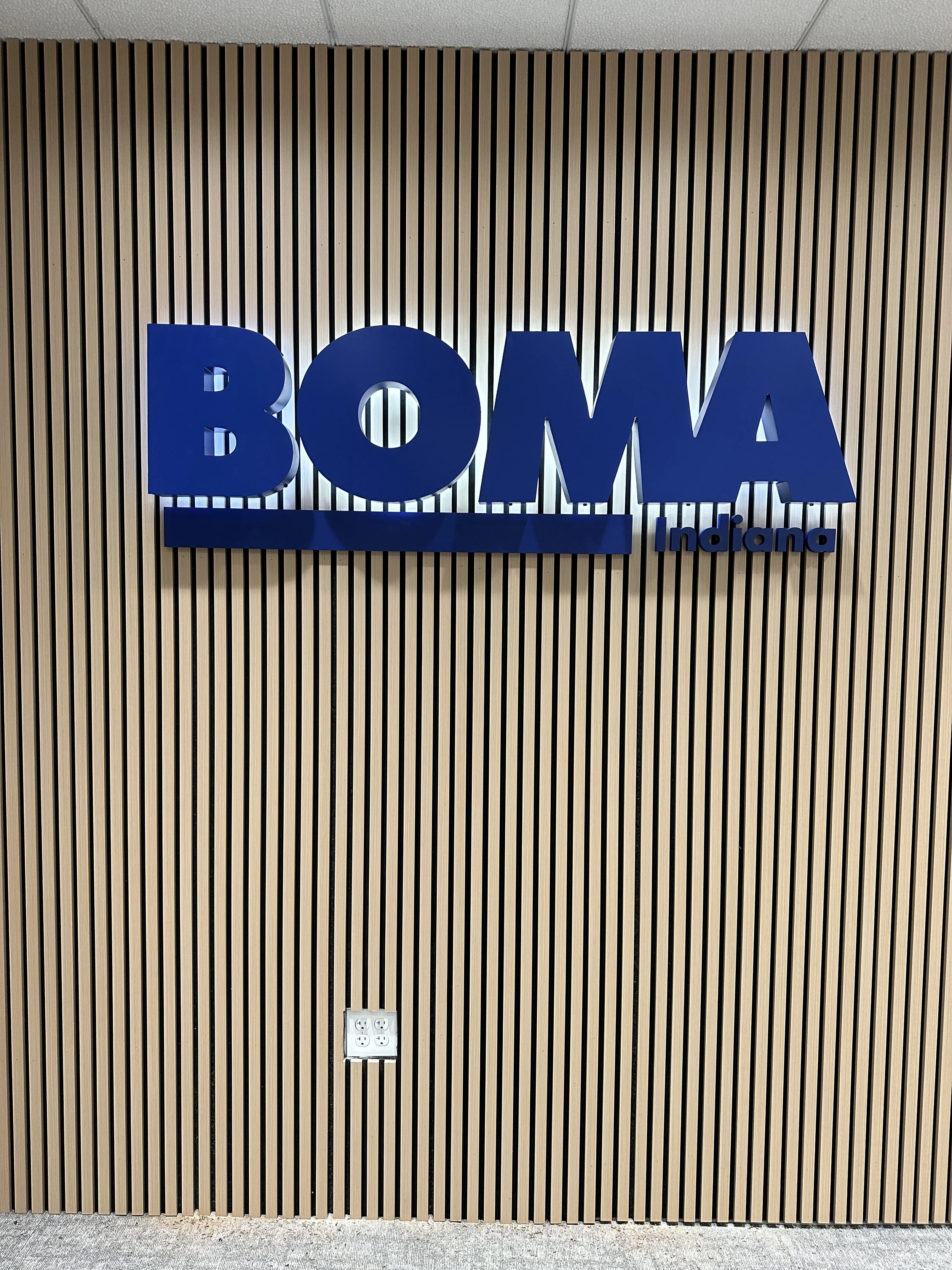 Blue 3D sign reading 'BOMA Indiana' mounted on a wood slat wall.