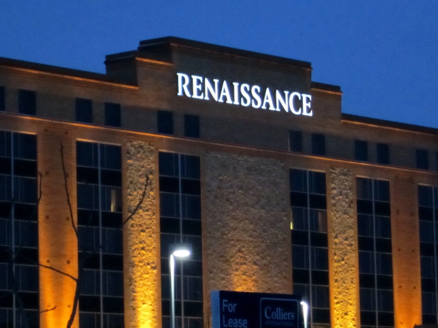 Night view of a brick hotel building with illuminated sign reading 'Renaissance' at the top.