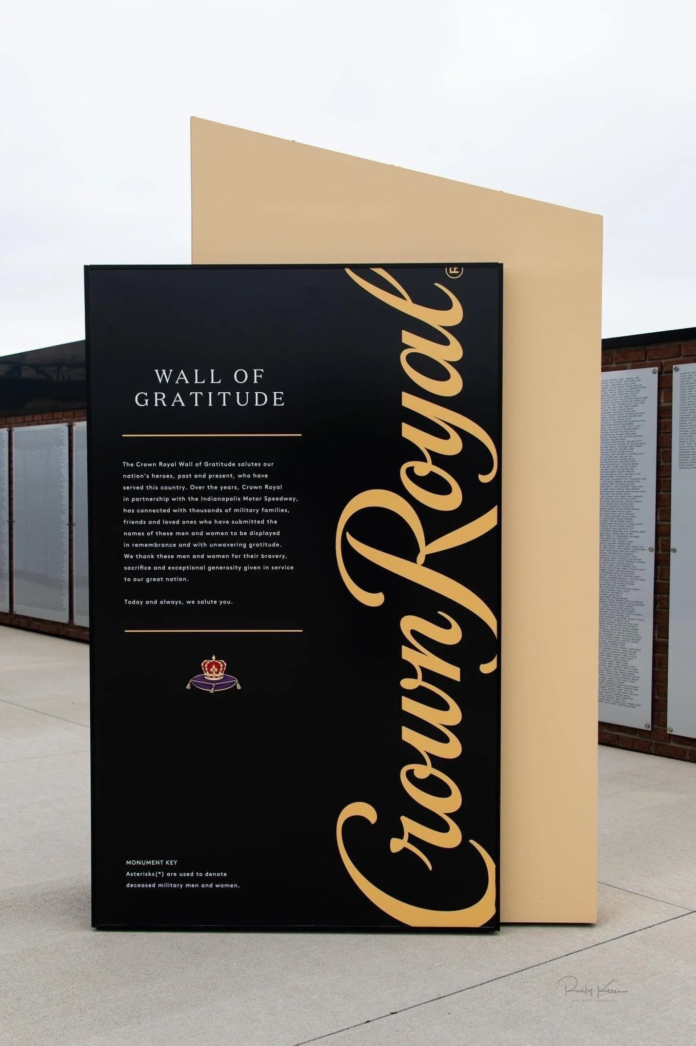 An outdoor memorial wall titled 'Wall of Gratitude' with text dedicated to military heroes, featuring a large 'Crown Royal' logo overlay.