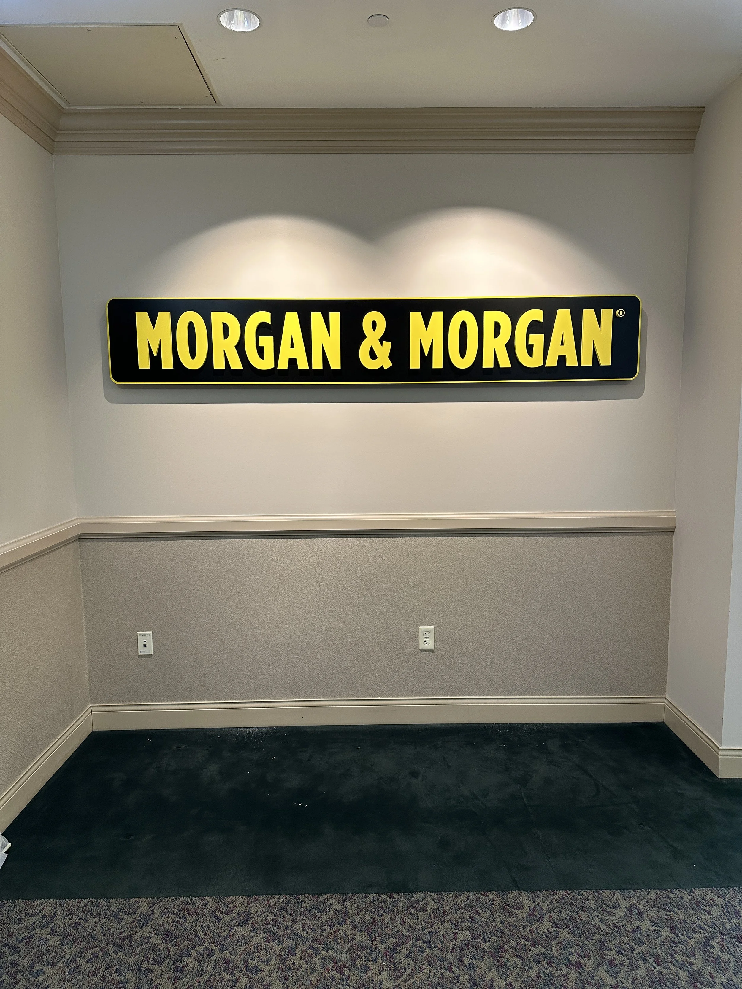 Empty interior wall with a black and yellow sign reading 'Morgan & Morgan'