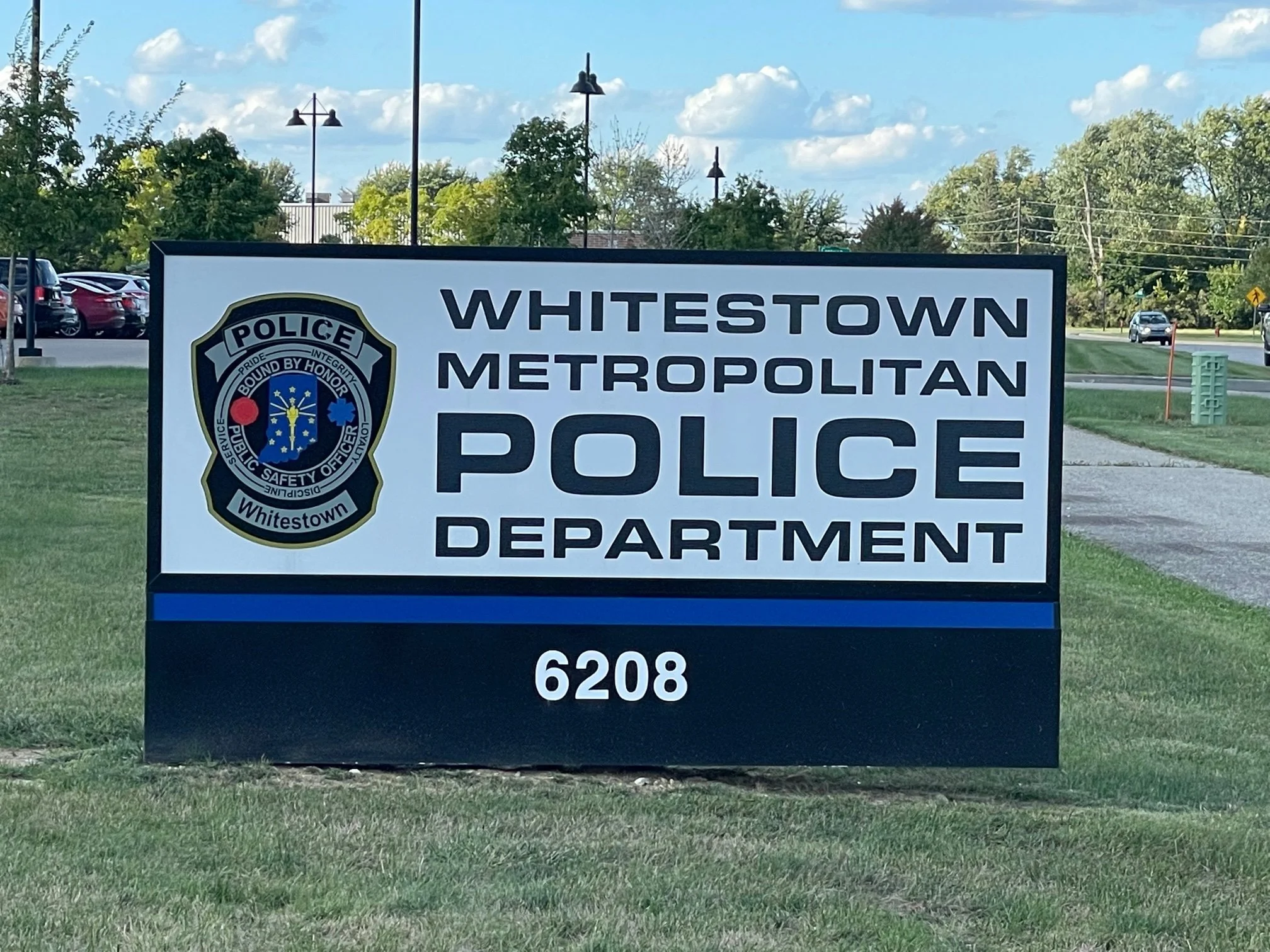 Sign for the Whitestown Metropolitan Police Department with police badge logo and the street number 6208.