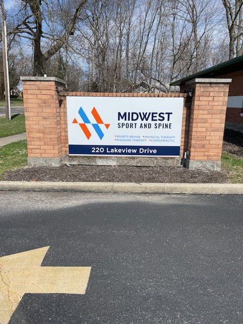 Sign for Midwest Sport and Spine with logos and address at 220 Lakeview Drive, located outside.