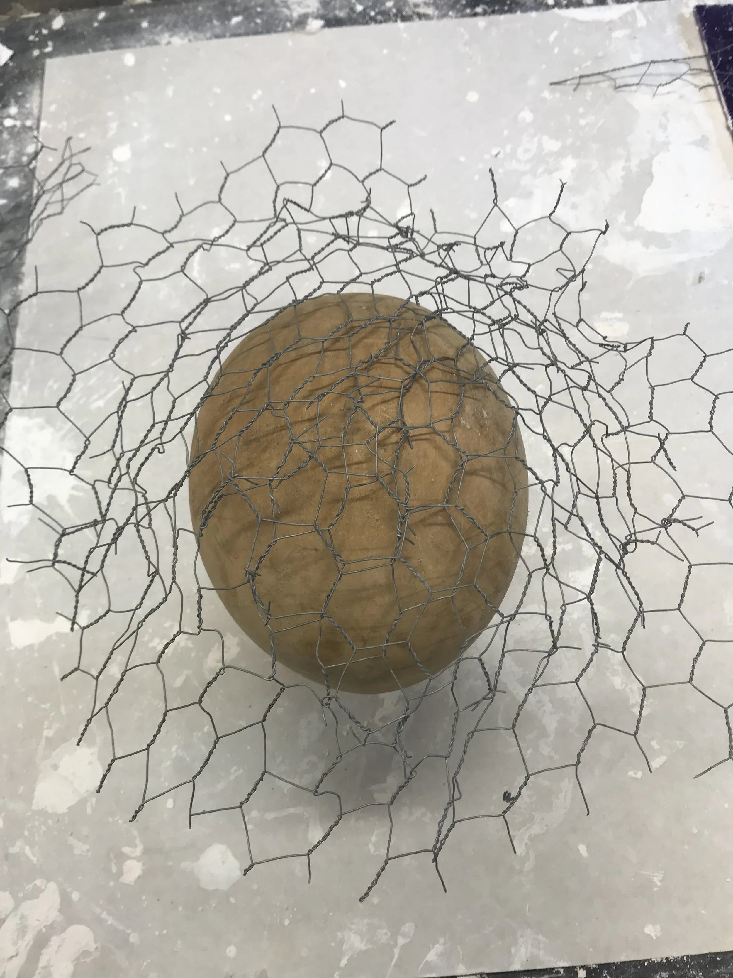 Moulded chicken wire around a head stand.
