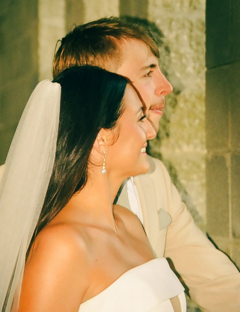 A bride and groom smiling side by side during their wedding ceremony.
