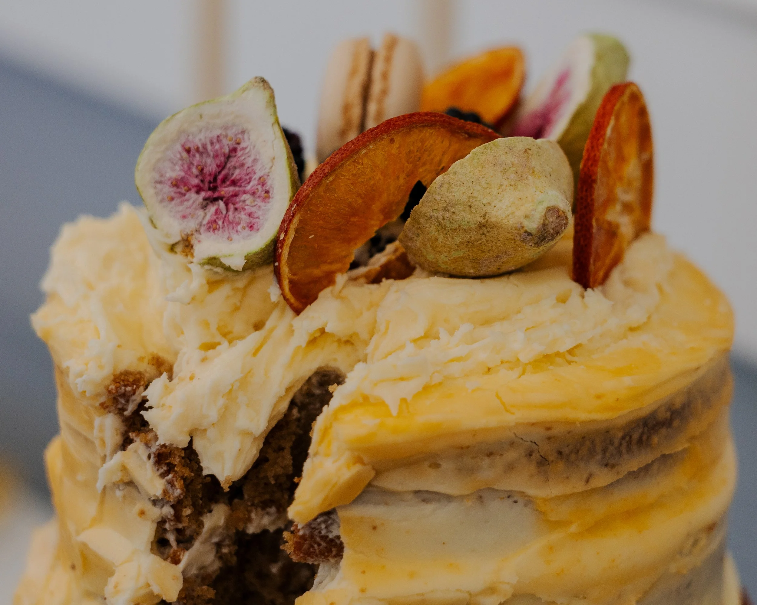 A slice of cake topped with various dried fruits including fig, orange, and apricot slices, and a small cookie or biscuit.