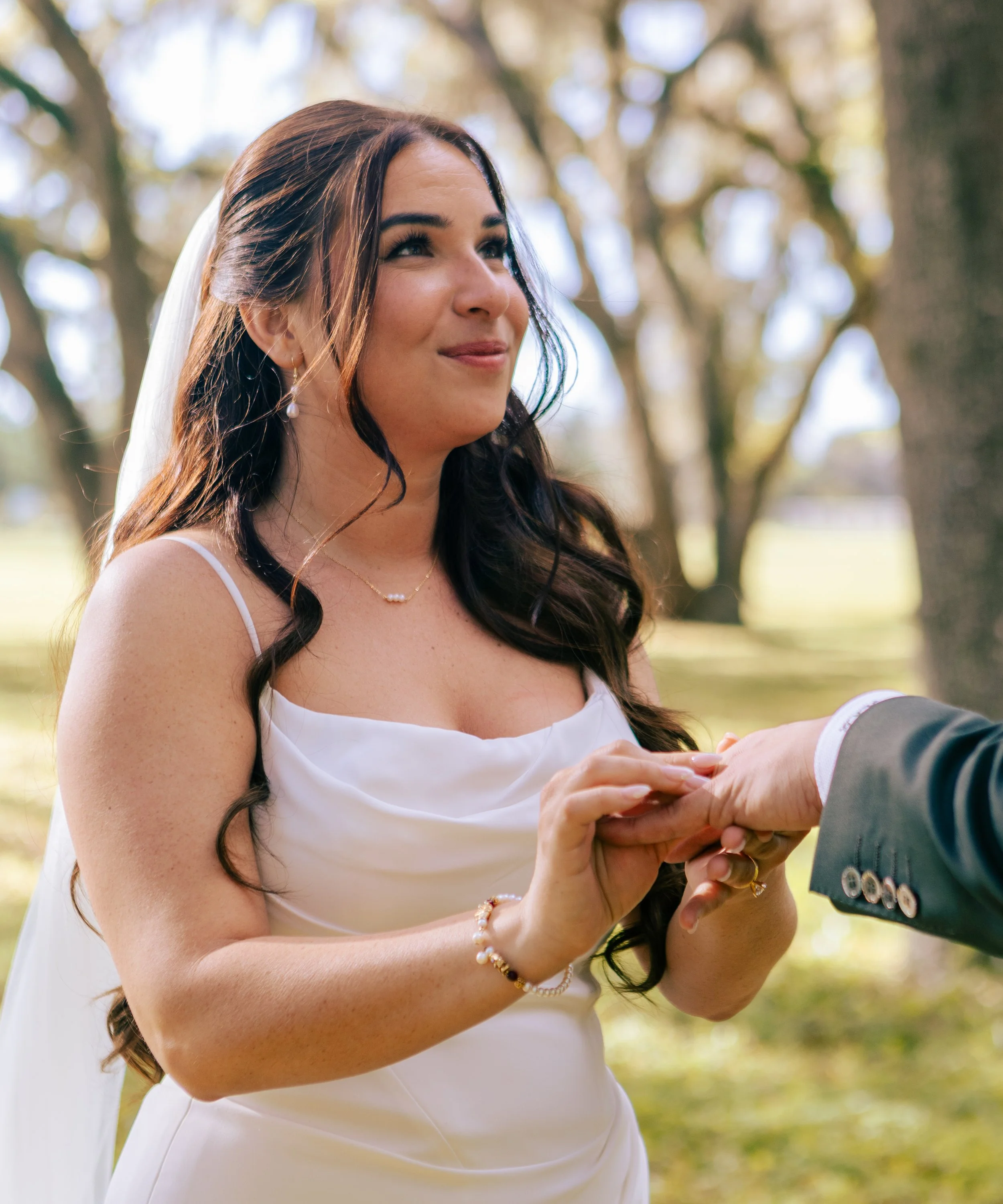 Bride placing a wedding ring on her new husband's ring finger at a nature preserve venue in Ocala, Florida.