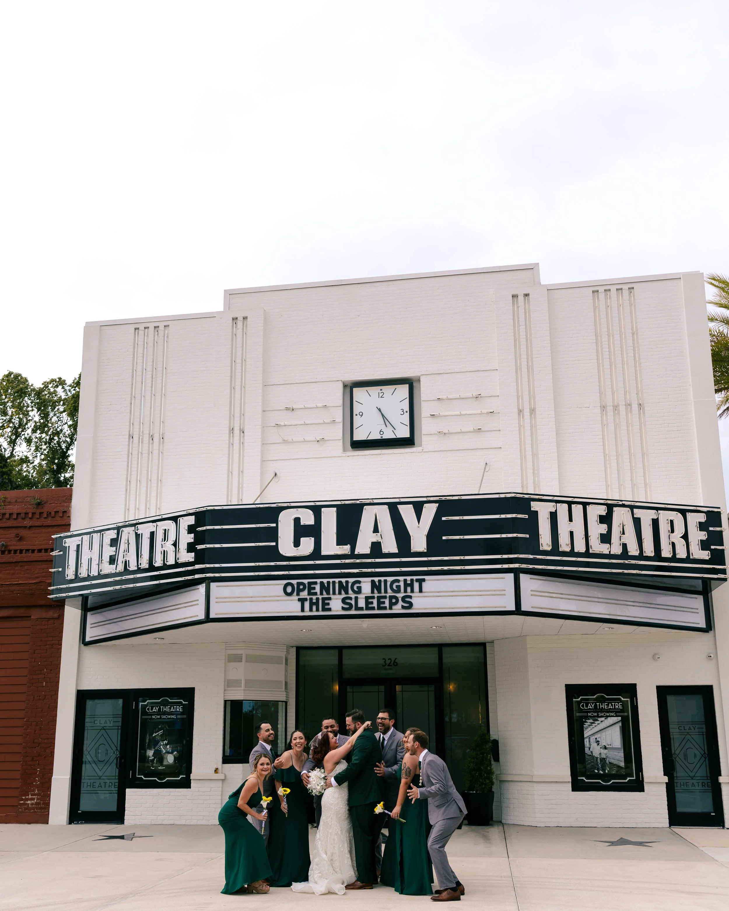 Wedding party standing outside the Clay Theatre, with a group of people smiling and posing for the photo.