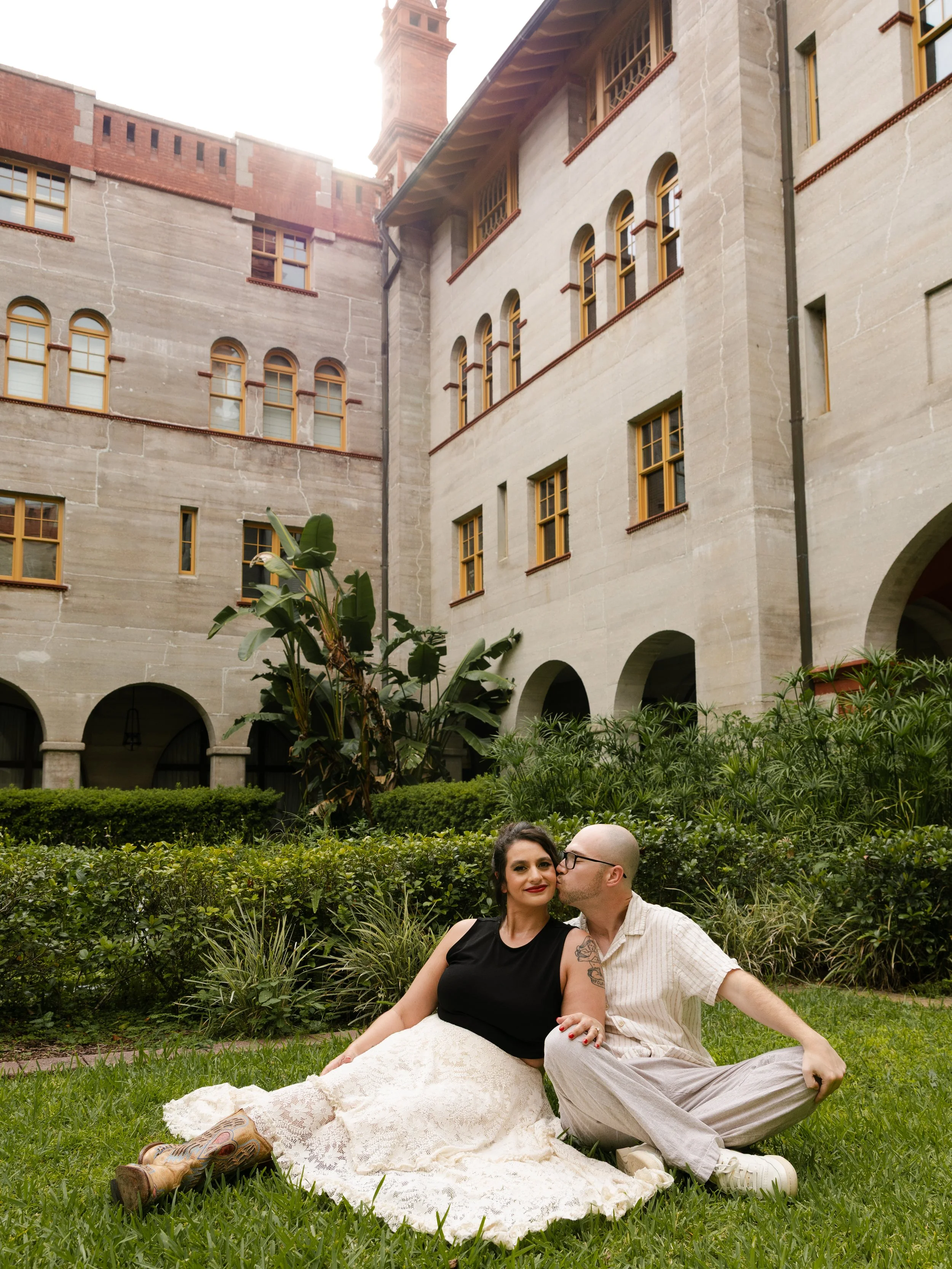 Engaged couple sits closely in the garden of the Lightner Museum in St. Augustine, Florida.