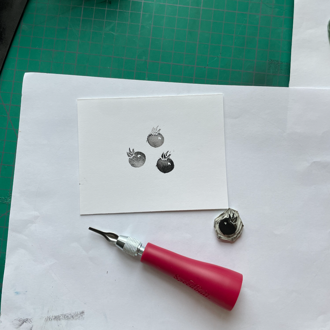 A linocut tool next to a berry linocut print. Example for creative retreat activities