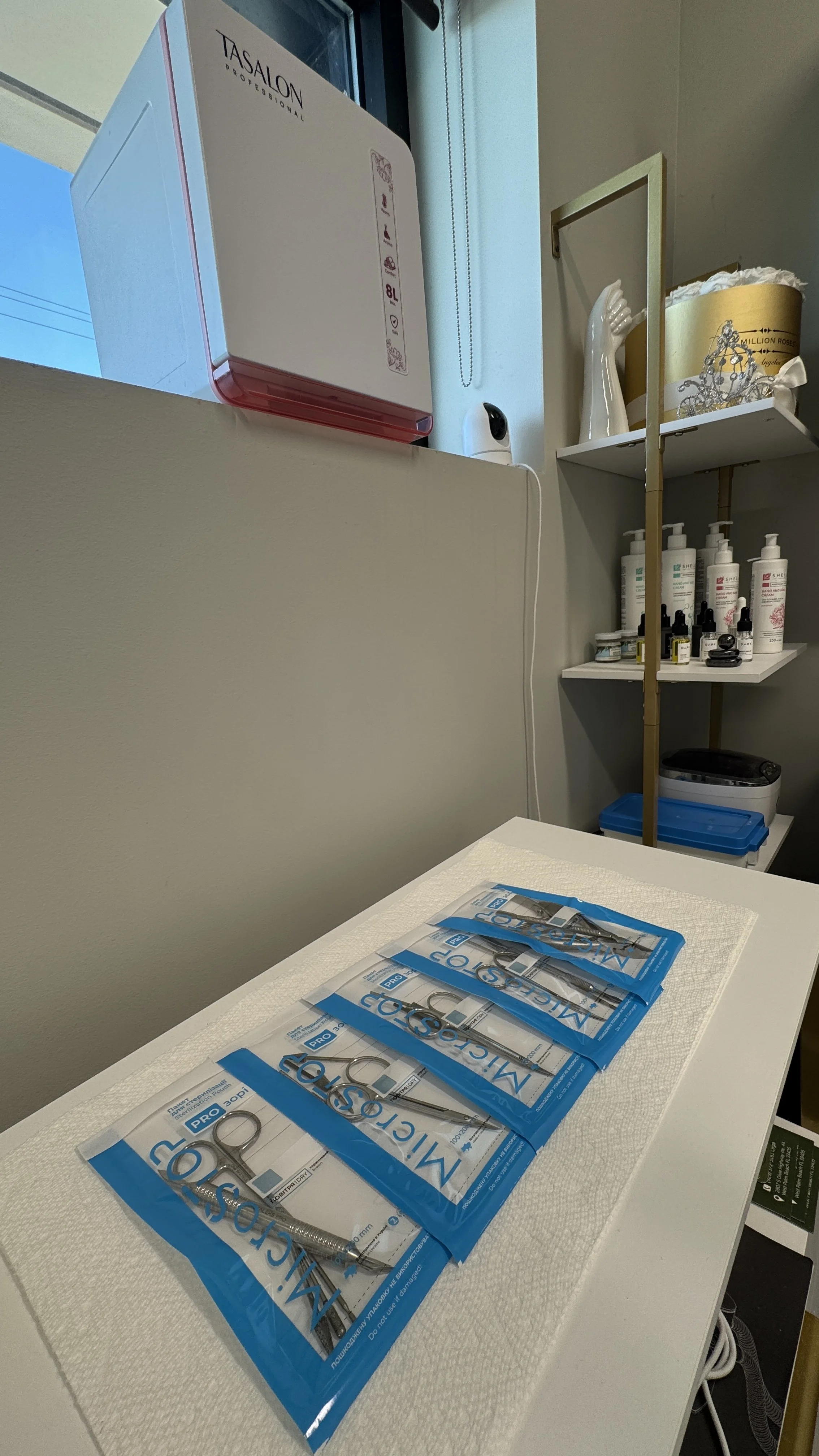 Five packaged medical or dental forceps laid out on a white table with a textured surface in a clinical setting.