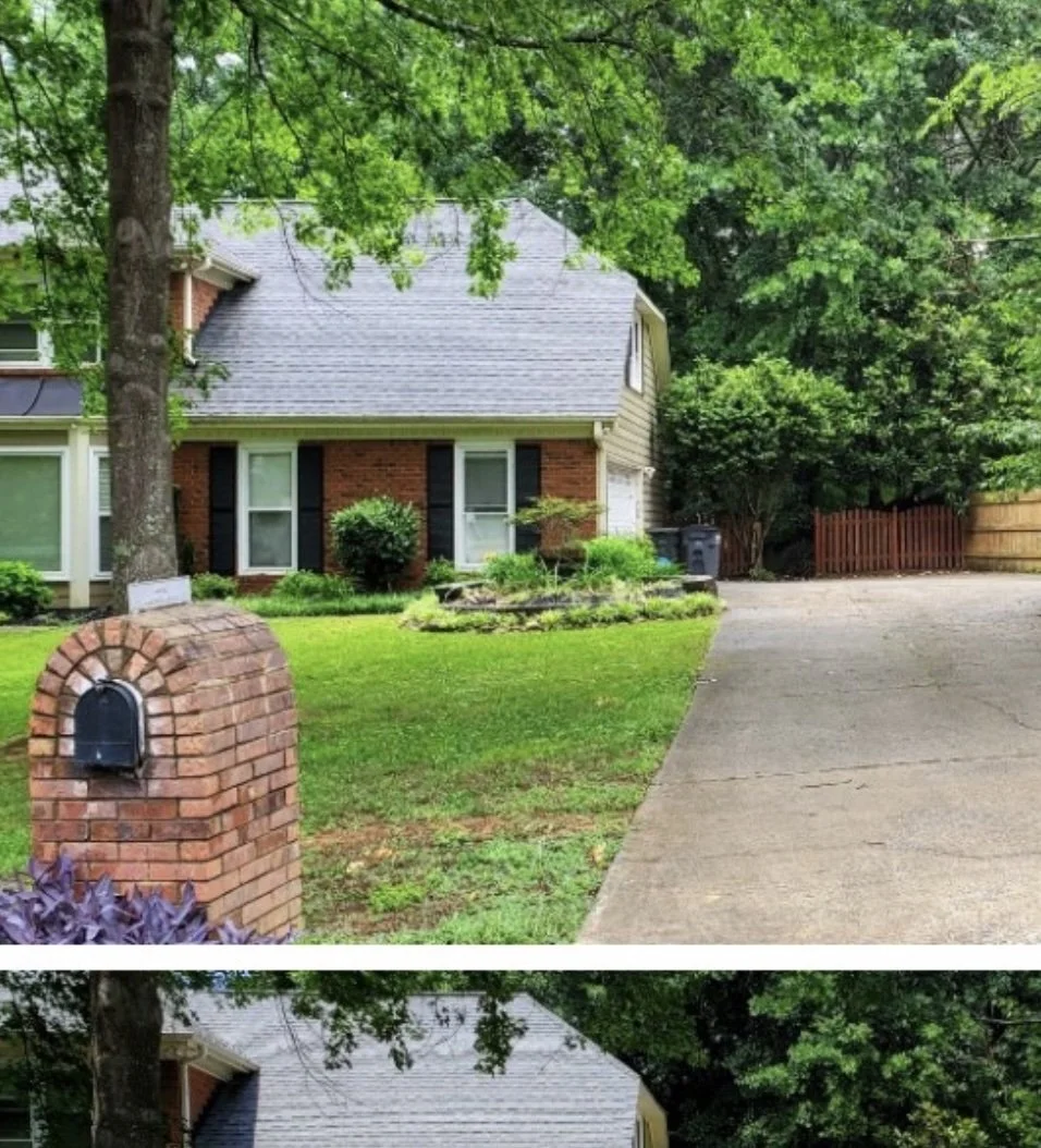 A house with a front yard, brick mailbox, and driveway surrounded by trees and greenery.