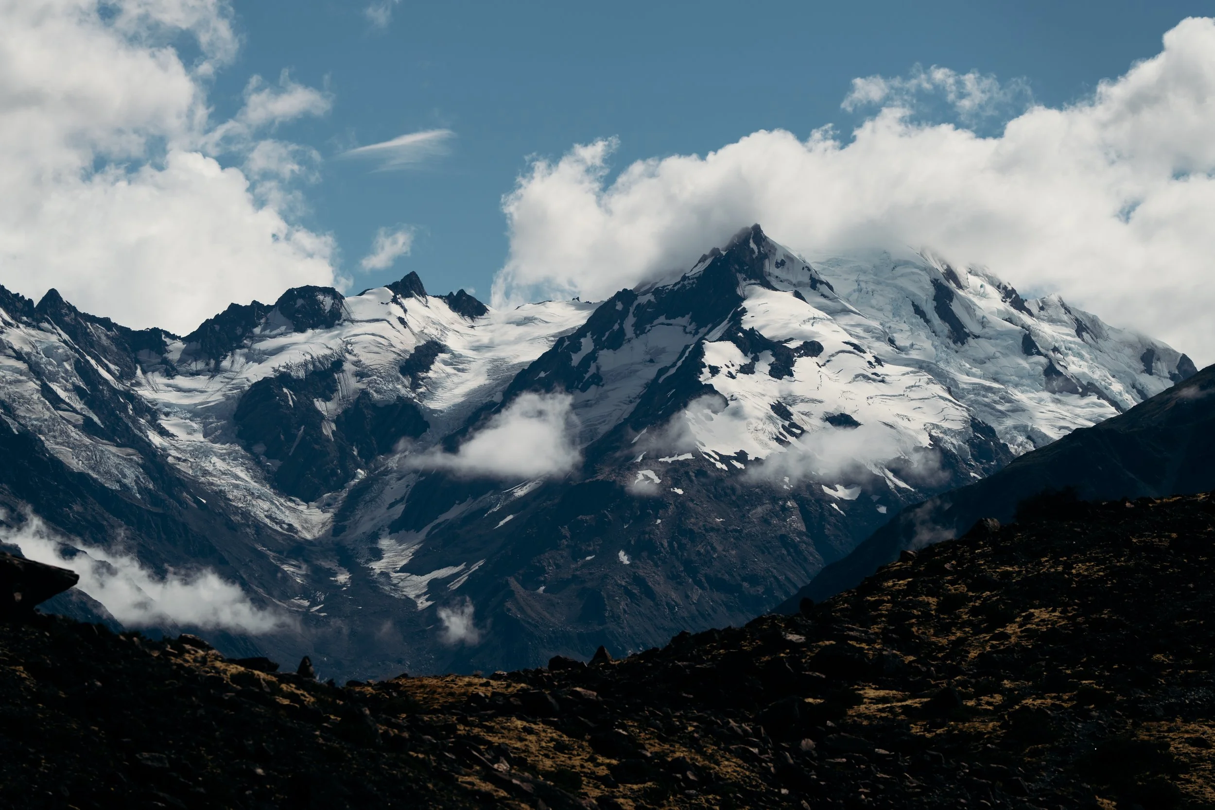 New Zealand's Mount Cooke, a snow-capped mountain range under a cloudy sky.