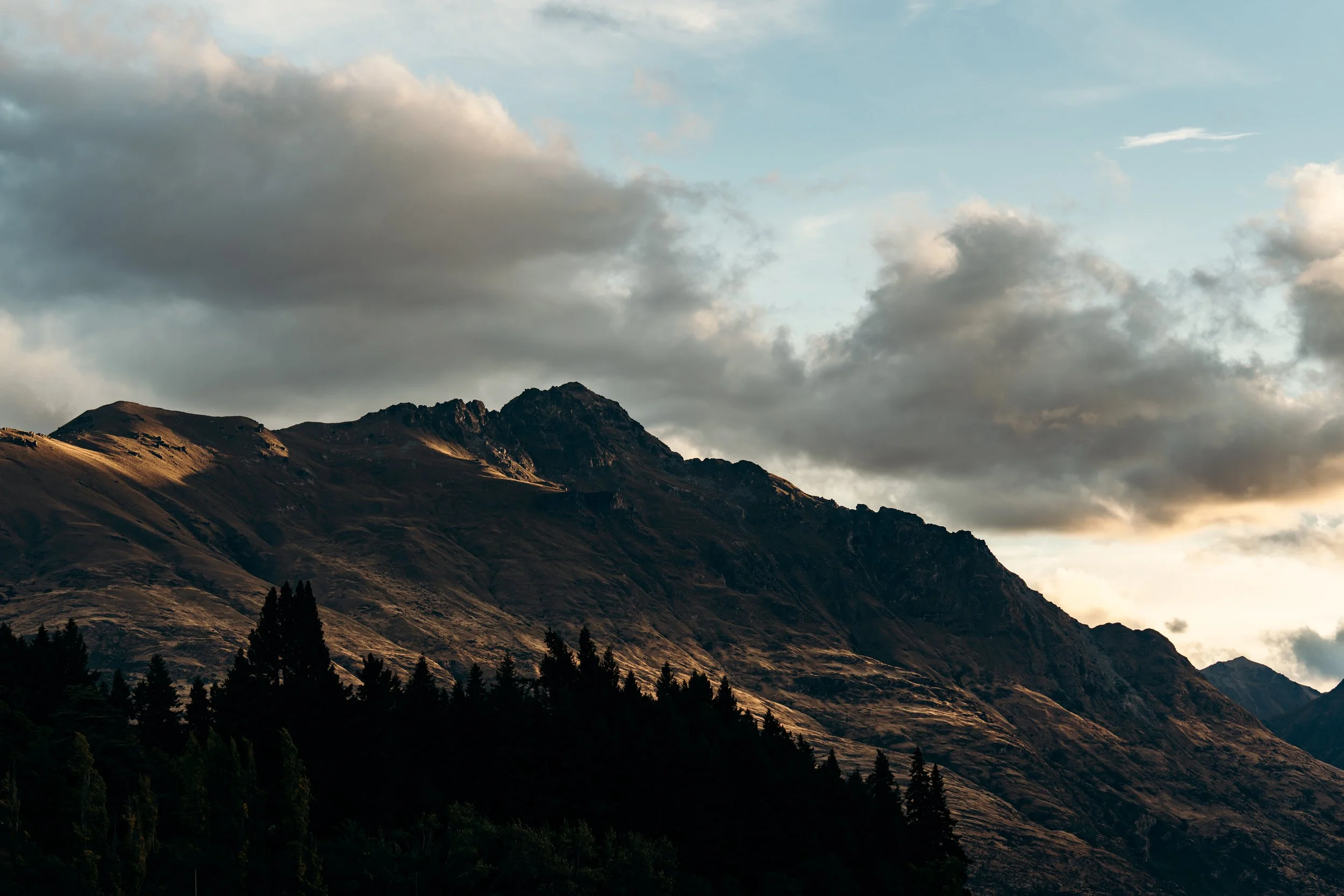 Scenic view of mountain range under cloudy sky with forested foreground.
