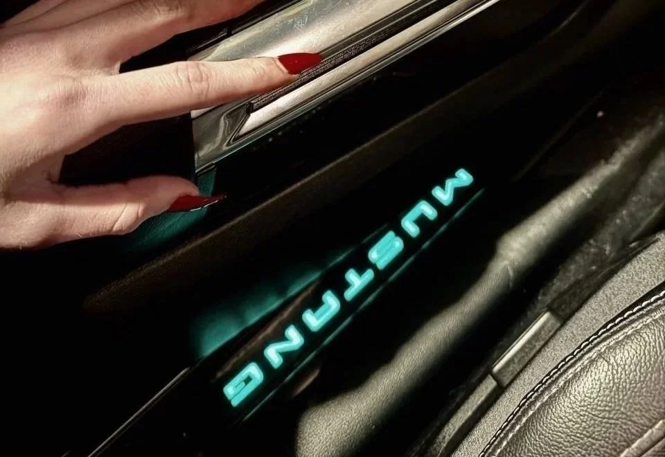 Close-up of illuminated Mustang logo inside a Ford Mustang, part of a modern classic performance car.