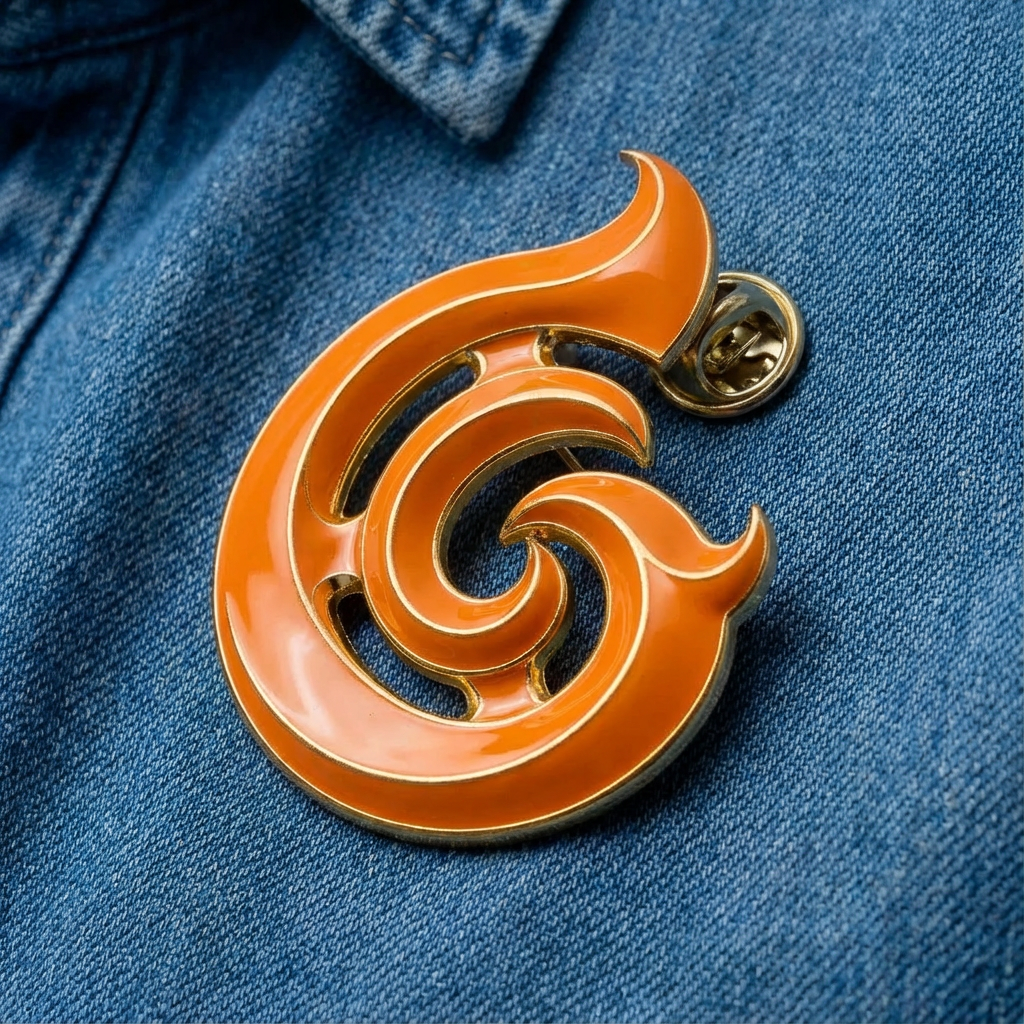 A large, decorative, orange and gold lapel pin in the shape of a stylized number six, worn on a blue denim fabric.