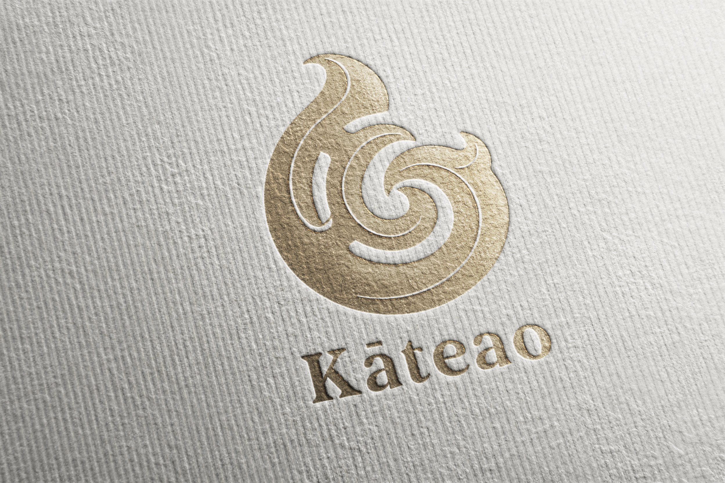 Close-up of a textured paper with a gold embossed swirl logo and the name 'Käteao' beneath.