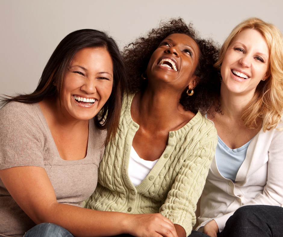 Three women sitting next to each other joyously laughing.Reclaiming_HER_Resilience_website