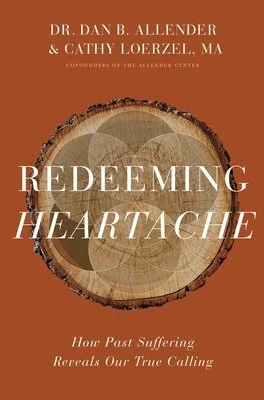 Book cover with brown background, wooden cross-section in center, and title 'Redeeming Heartache' by Dr. Dan B. Allender and Cathy Loerzel, addressing how past suffering reveals our true calling. For Trauma-informed Care.