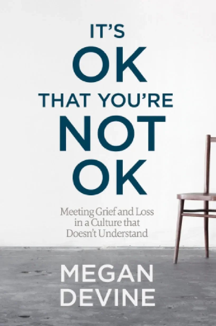 Book cover titled "It's OK That You're Not OK: Meeting Grief and Loss in a Culture that Doesn't Understand" by Megan Devine, featuring a wooden chair in a minimalist setting.