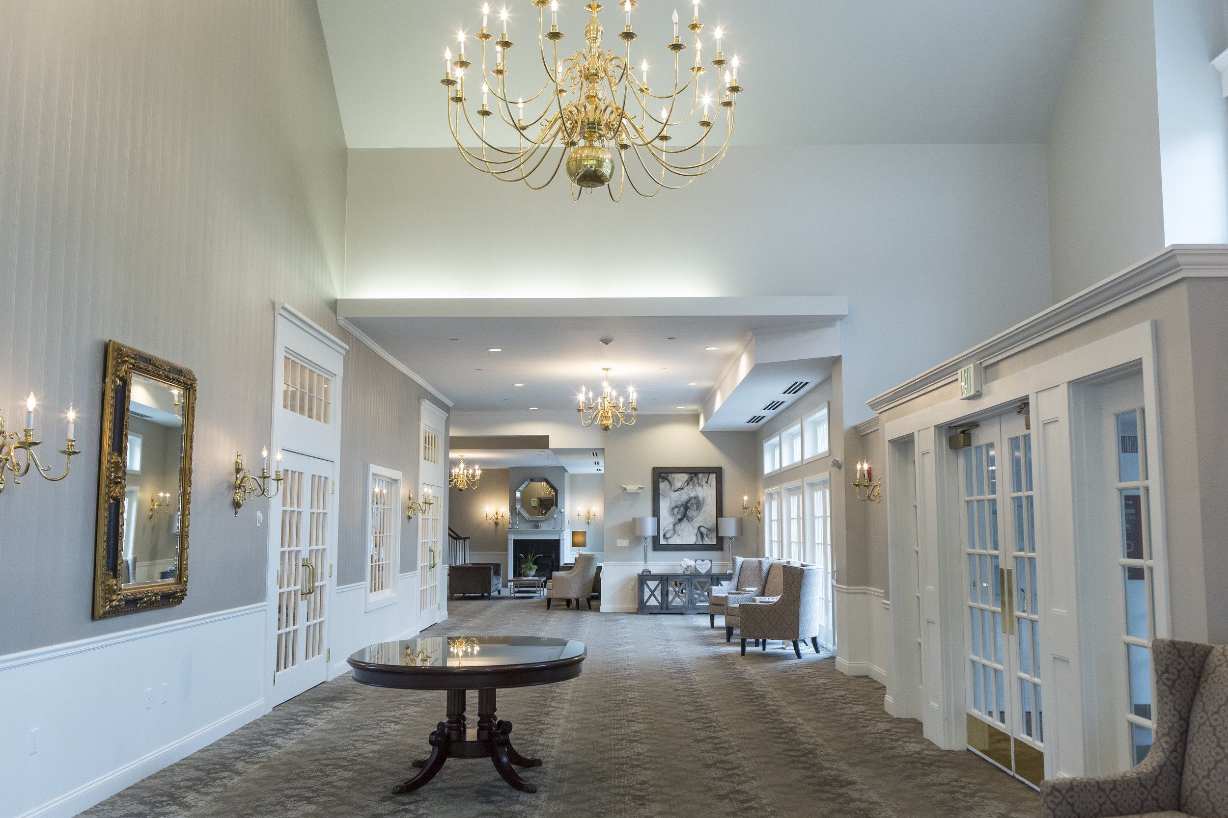 Elegant hotel lobby with chandeliers, gold accents, tall windows, and seating areas.