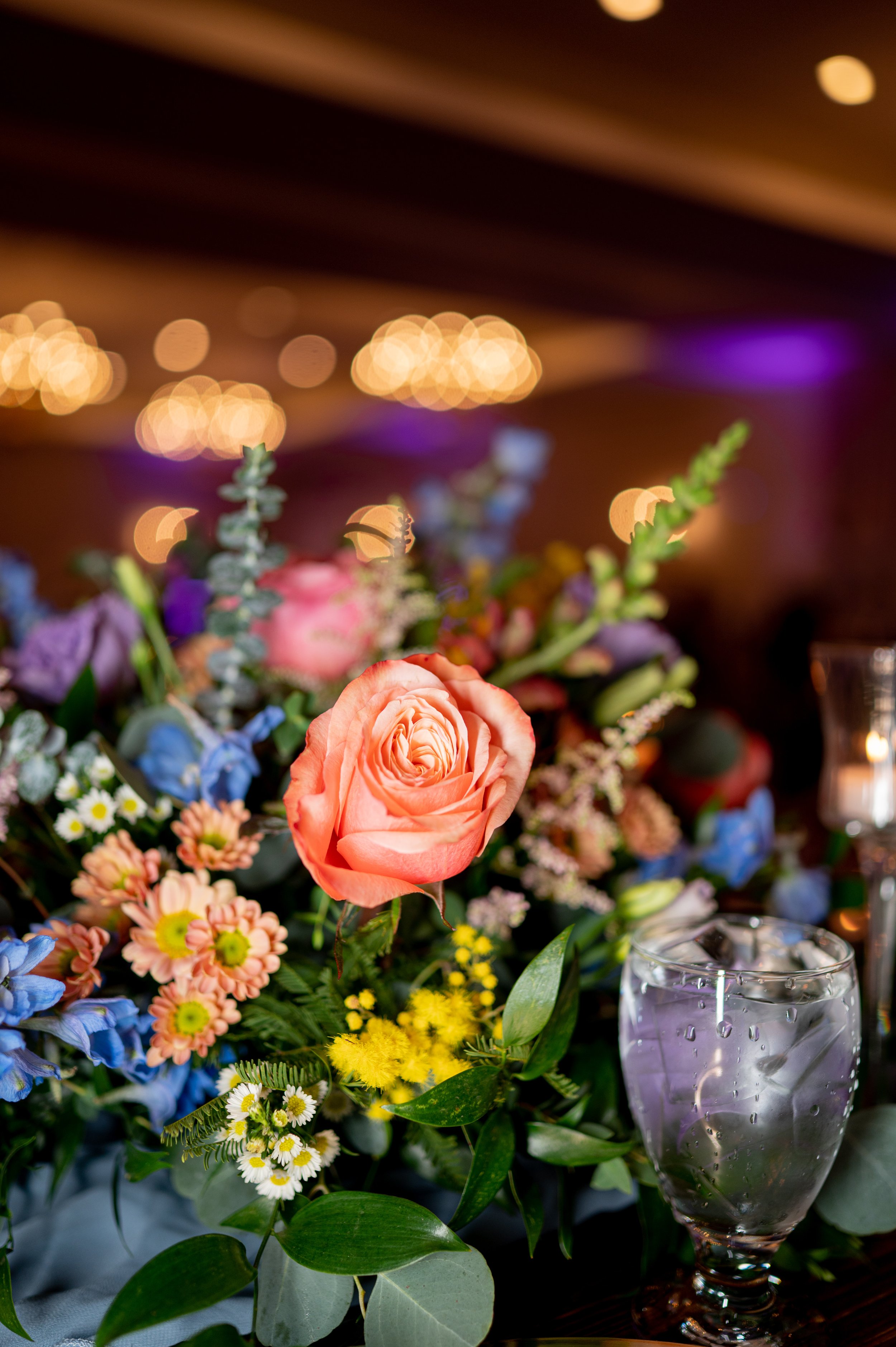 Decorative table centerpiece with three gold candle holders with glass orb tops, surrounded by four small white candle holders on a marble table.