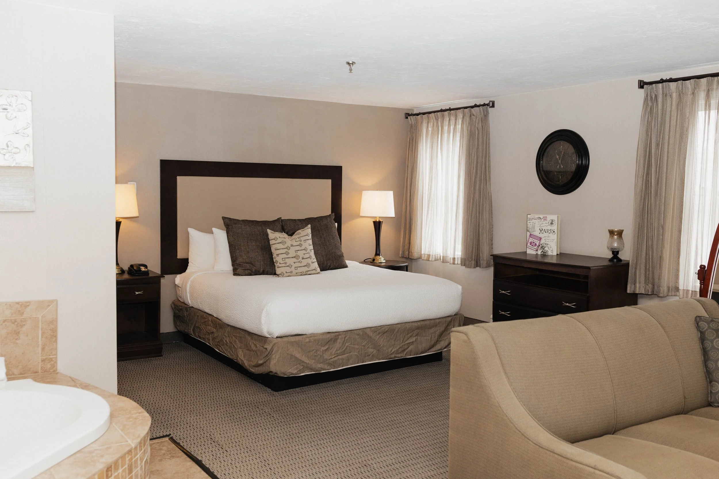 Hotel room with a bed, nightstands, lamps, and curtains.