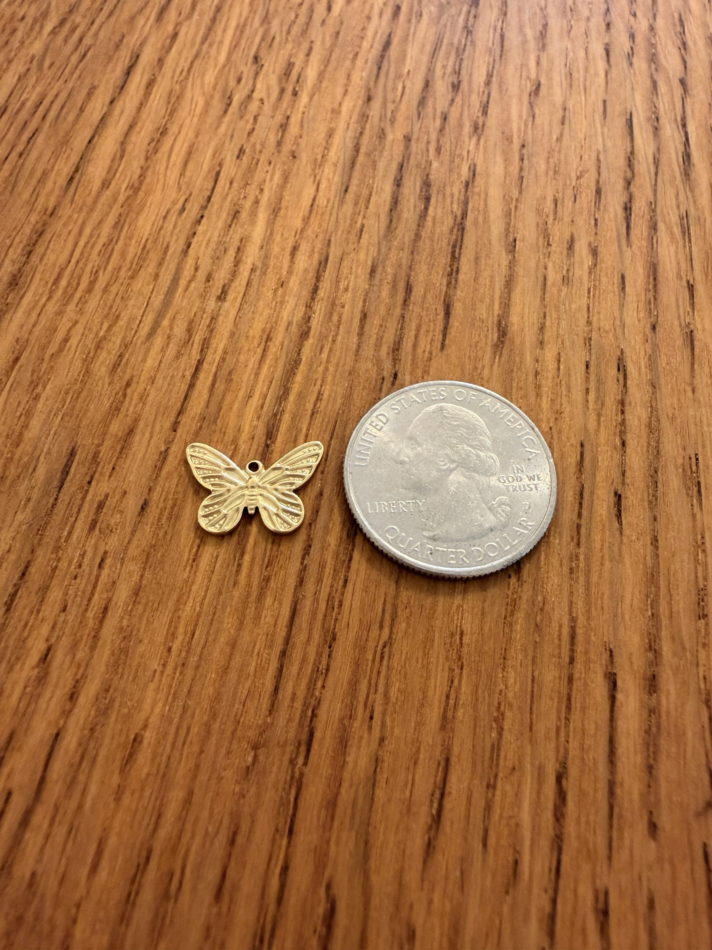 Butterfly Charm by House of Azelea with quarter on wood countertop