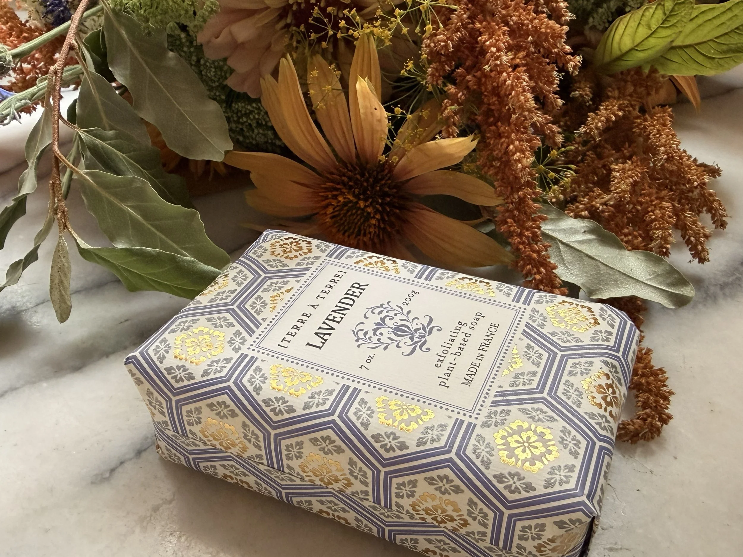 Side view of Terre á Terre Lavender Soap on marble with flowers