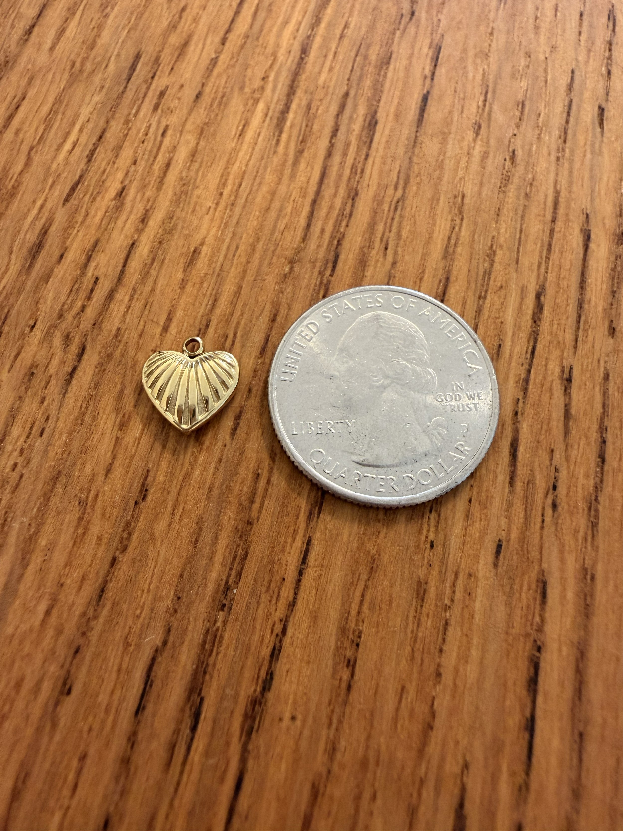One House of Azelea PVD Heart Charm on wood countertop with quarter