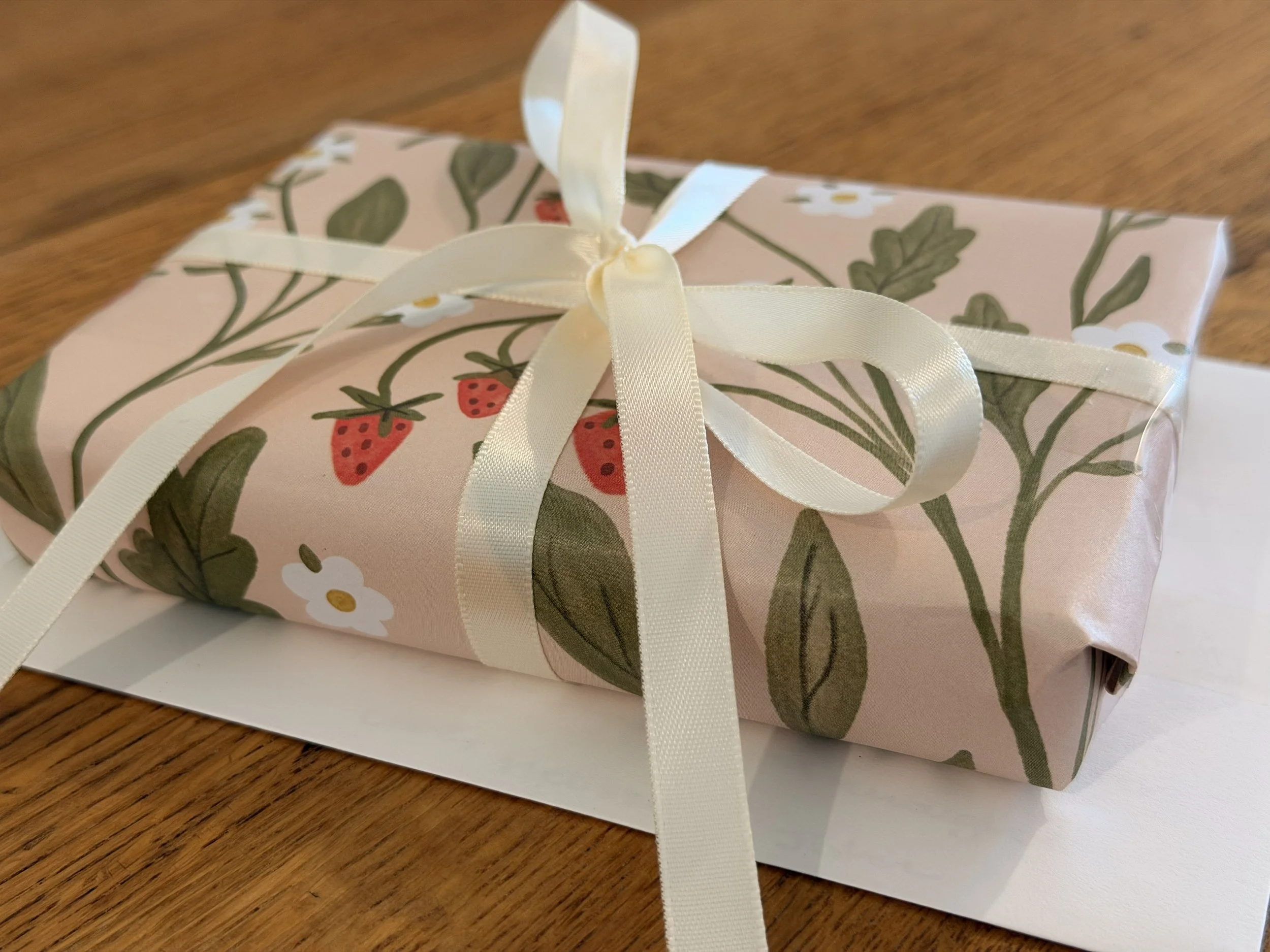 Small gift wrapped in Strawberry Fields wrapping paper by Ramona & Ruth and tied with a cream ribbon in a bow