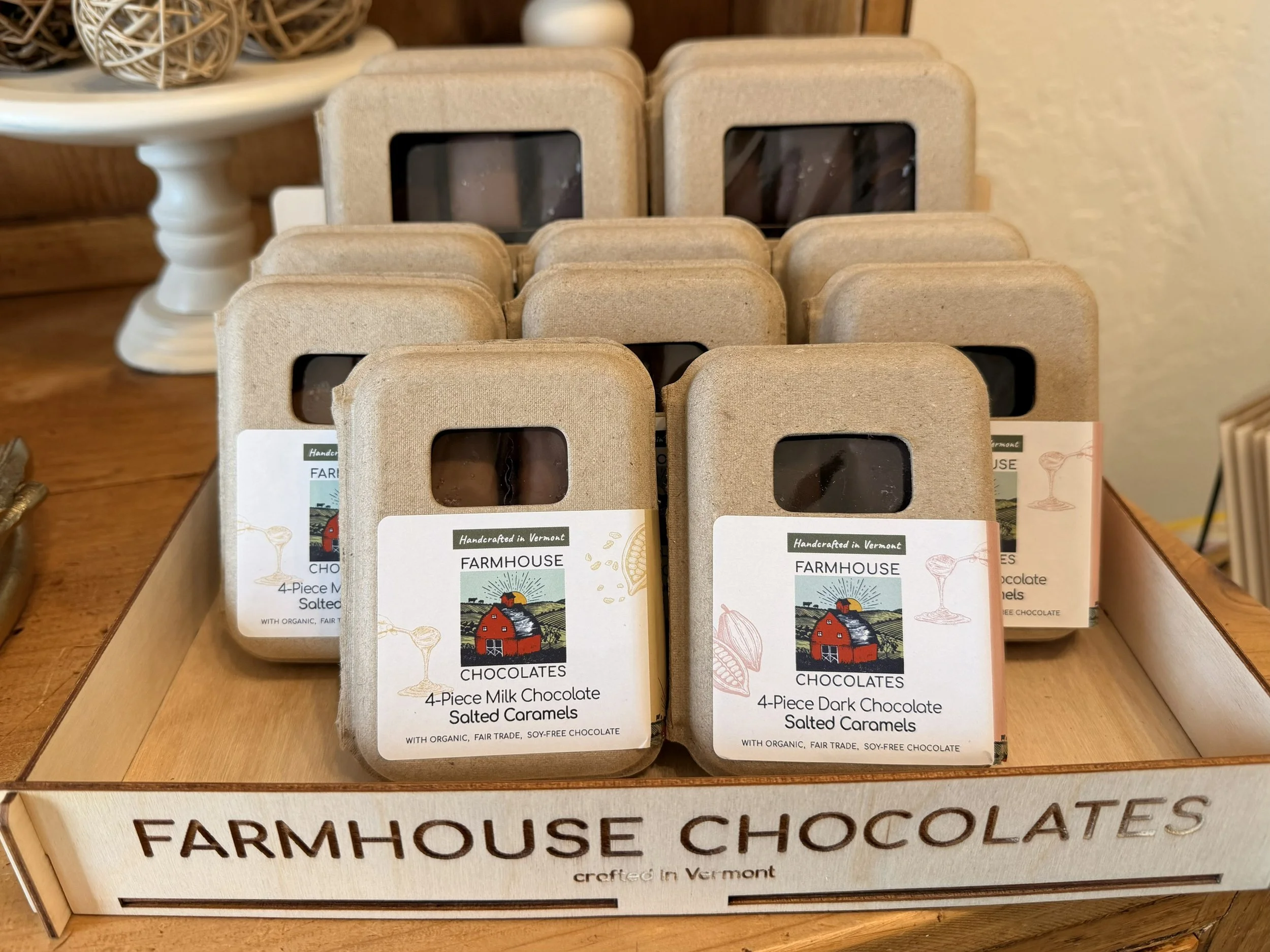 Display of Farmhouse Chocolates' 4-Piece Dark Chocolate Salted Caramels and more in recycled paper boxes on wood countertop