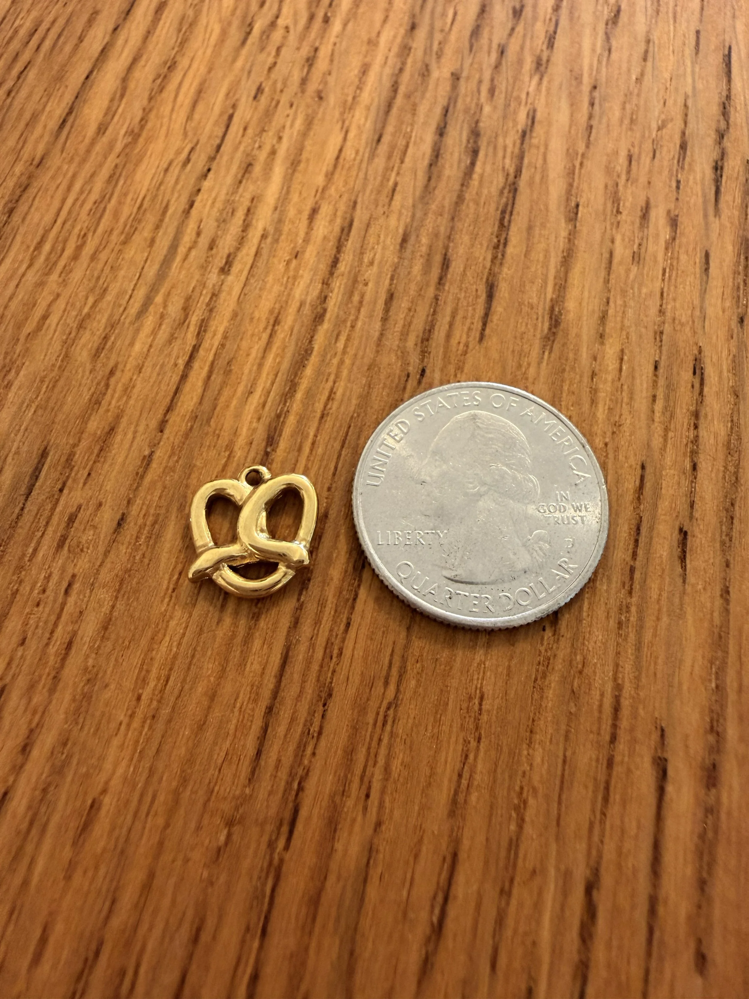 One Pretzel Charm by House of Azelea with quarter on wood countertop