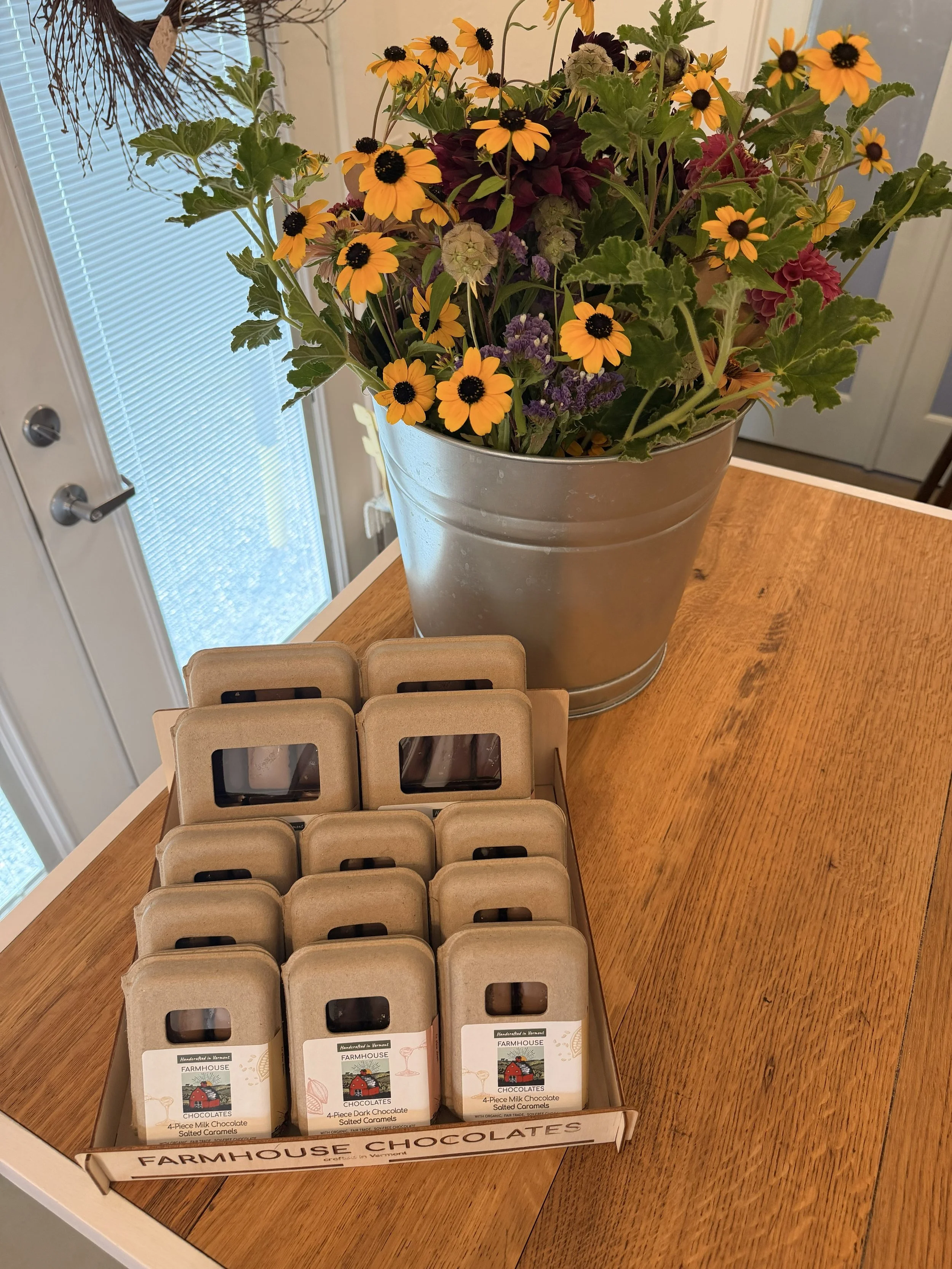 Display of Farmhouse Chocolates' 9 Piece Milk & Dark Chocolate Salted Caramels and more with flowers on wood countertop