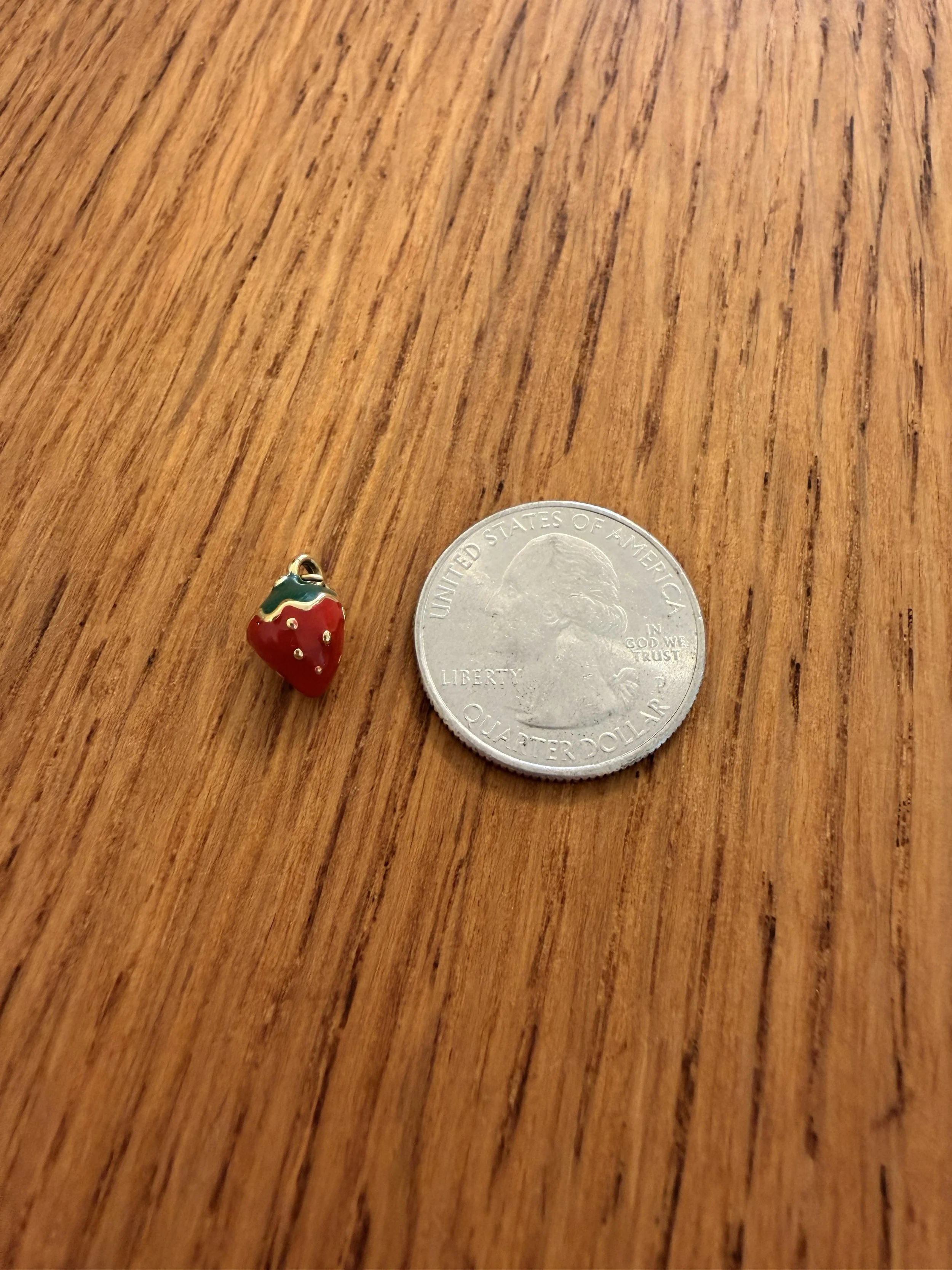 One Red Strawberry Charm by House of Azelea on wood countertop with quarter
